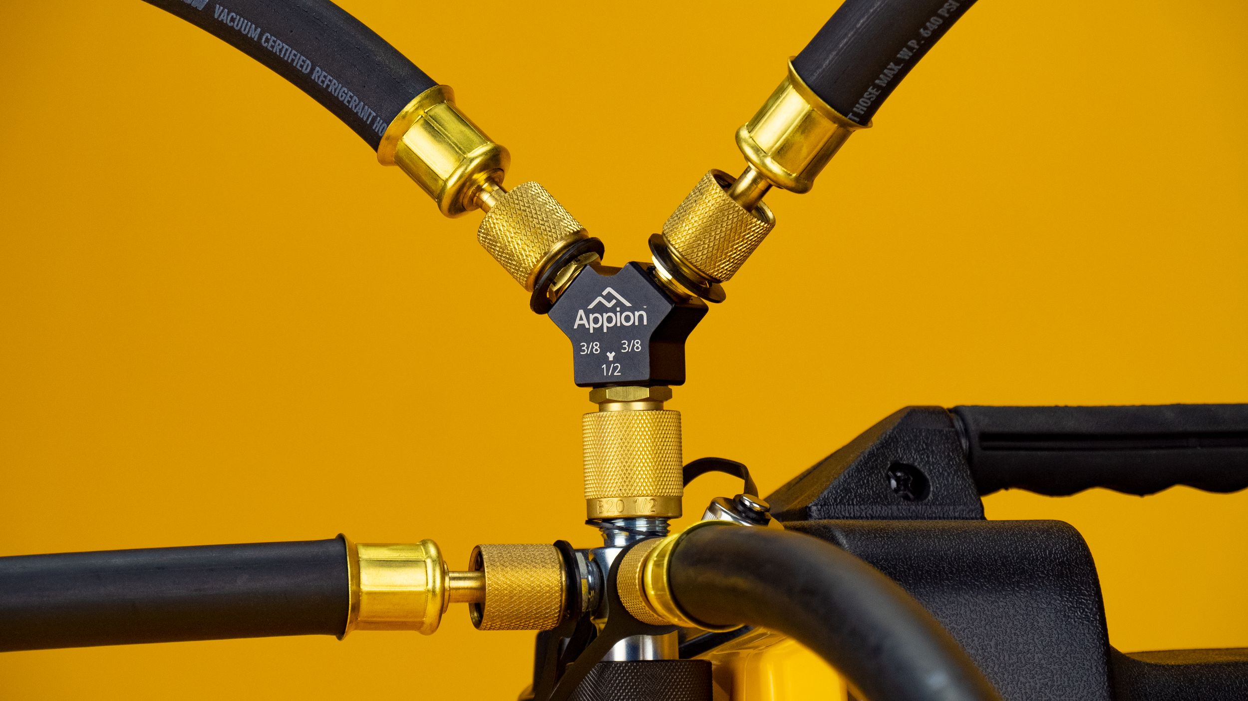 Close-up of a bicycle's handlebar with gold-colored connectors and a black Appion Y-connector against a yellow background.