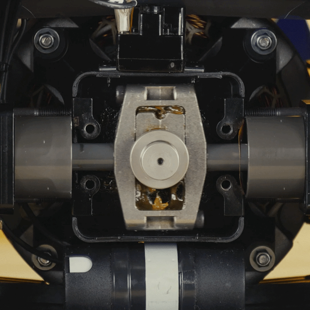 Close-up view of a drone's internal mechanical and electronic components, showing a central metal frame, motor mounts, and wiring.