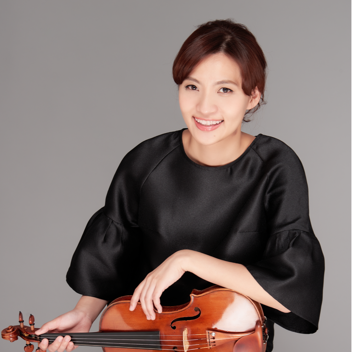 A woman smiling and holding a violin.