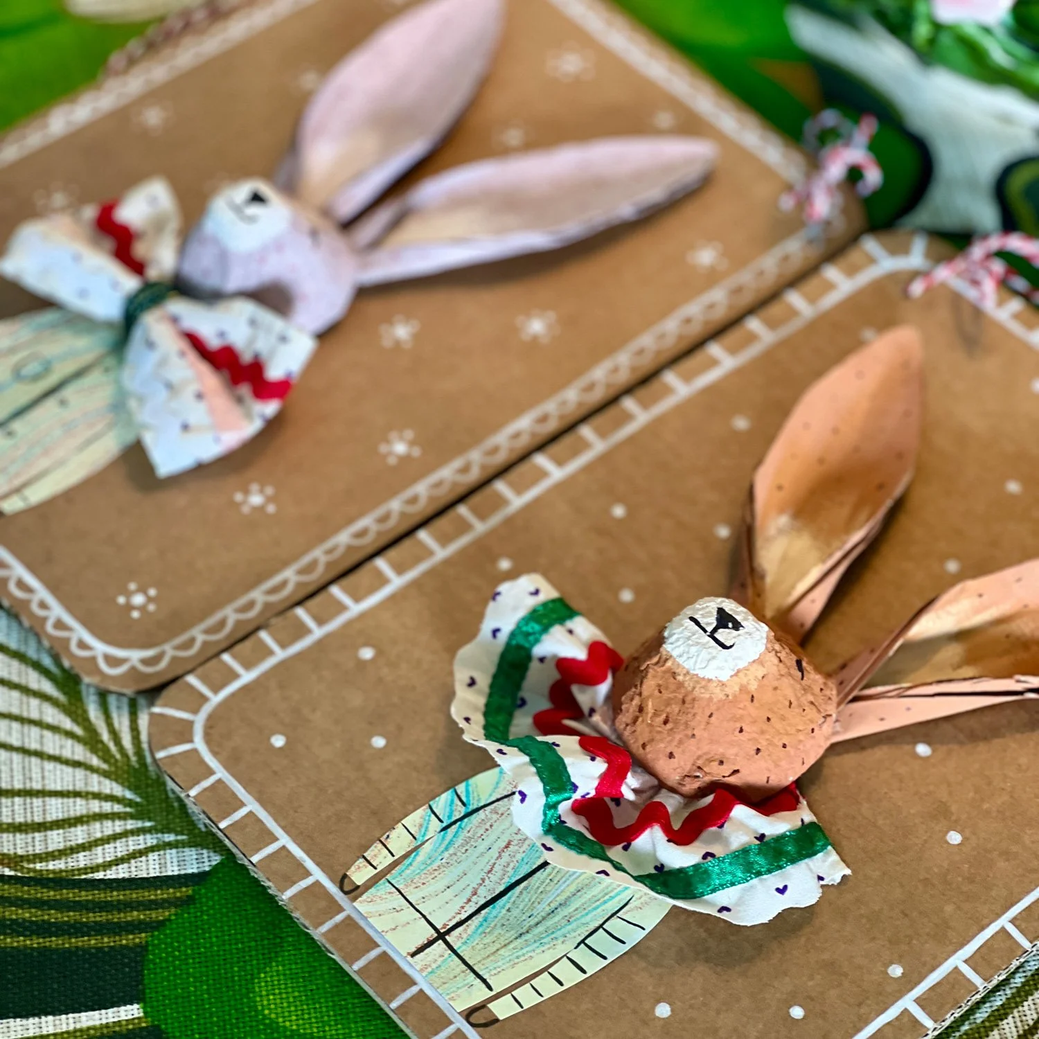 Two completed handmade cardboard bunnies with blue and red floral fabric bows, created in a creative workshop at Paper Caravan Newcastle West.