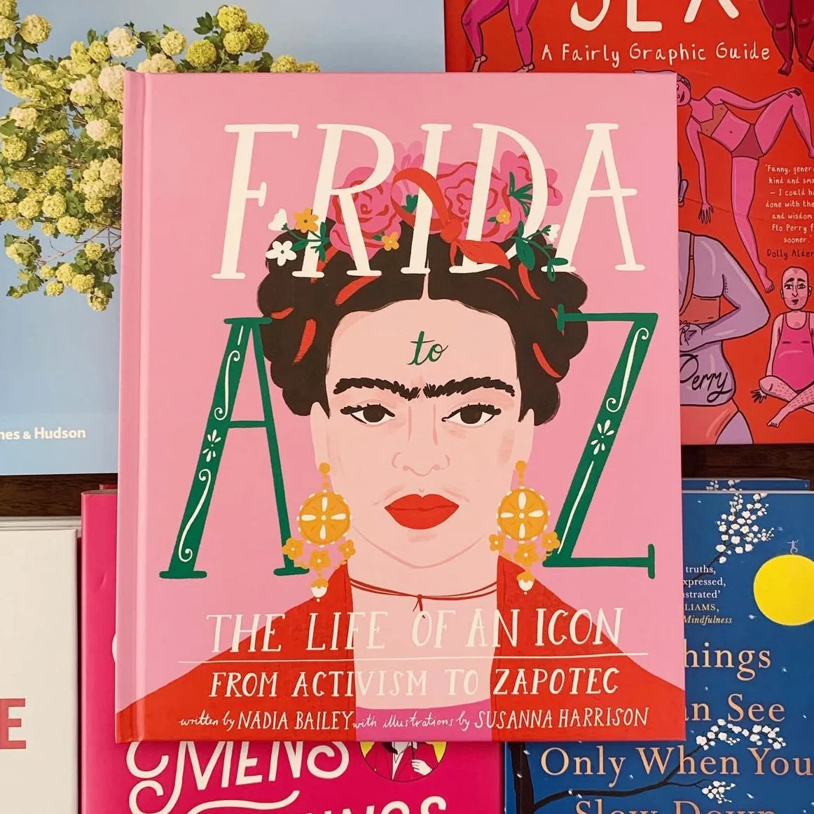 Book titled "Frida to AtoZ: The Life of an Icon From Activism to Zapotec" by Nadia Bailey with illustrations by Susanna Harrison, featuring an illustrated portrait of Frida Kahlo