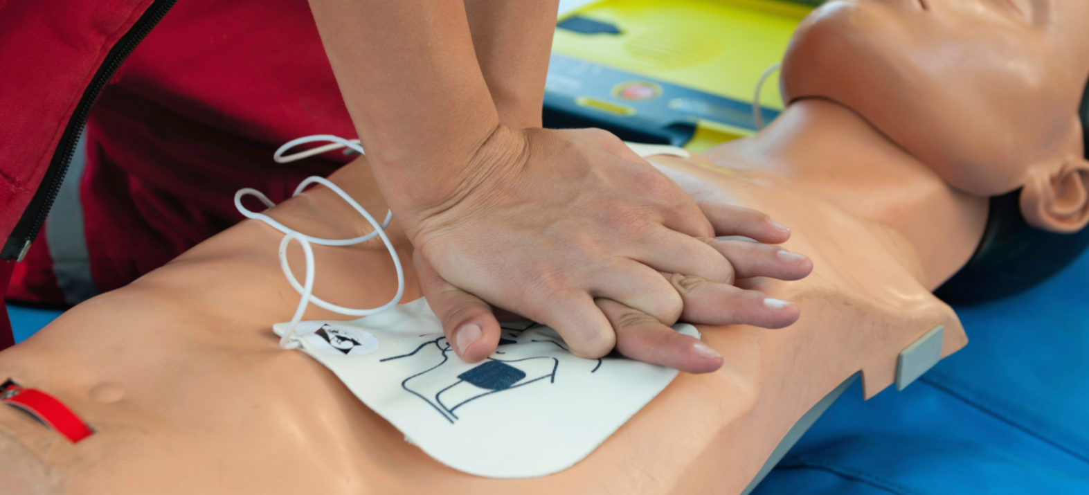 Person performing chest compressions on a CPR training mannequin during a CPR training session.