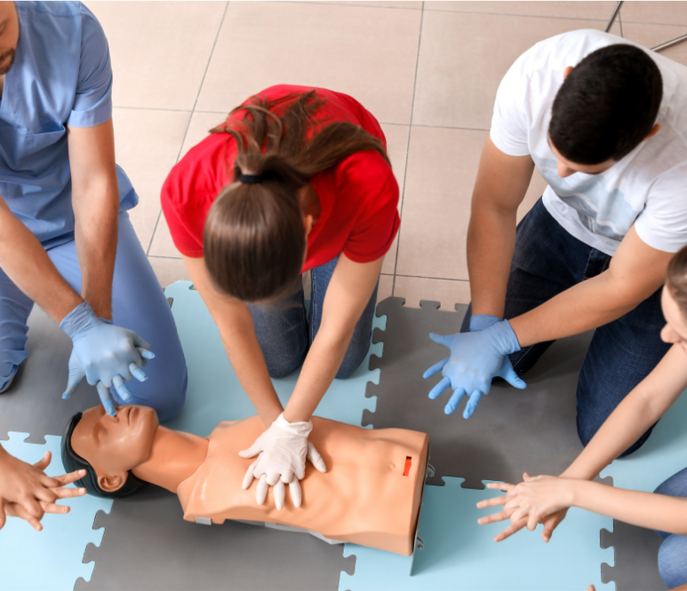 Group of people practicing CPR on a manikin in a training session