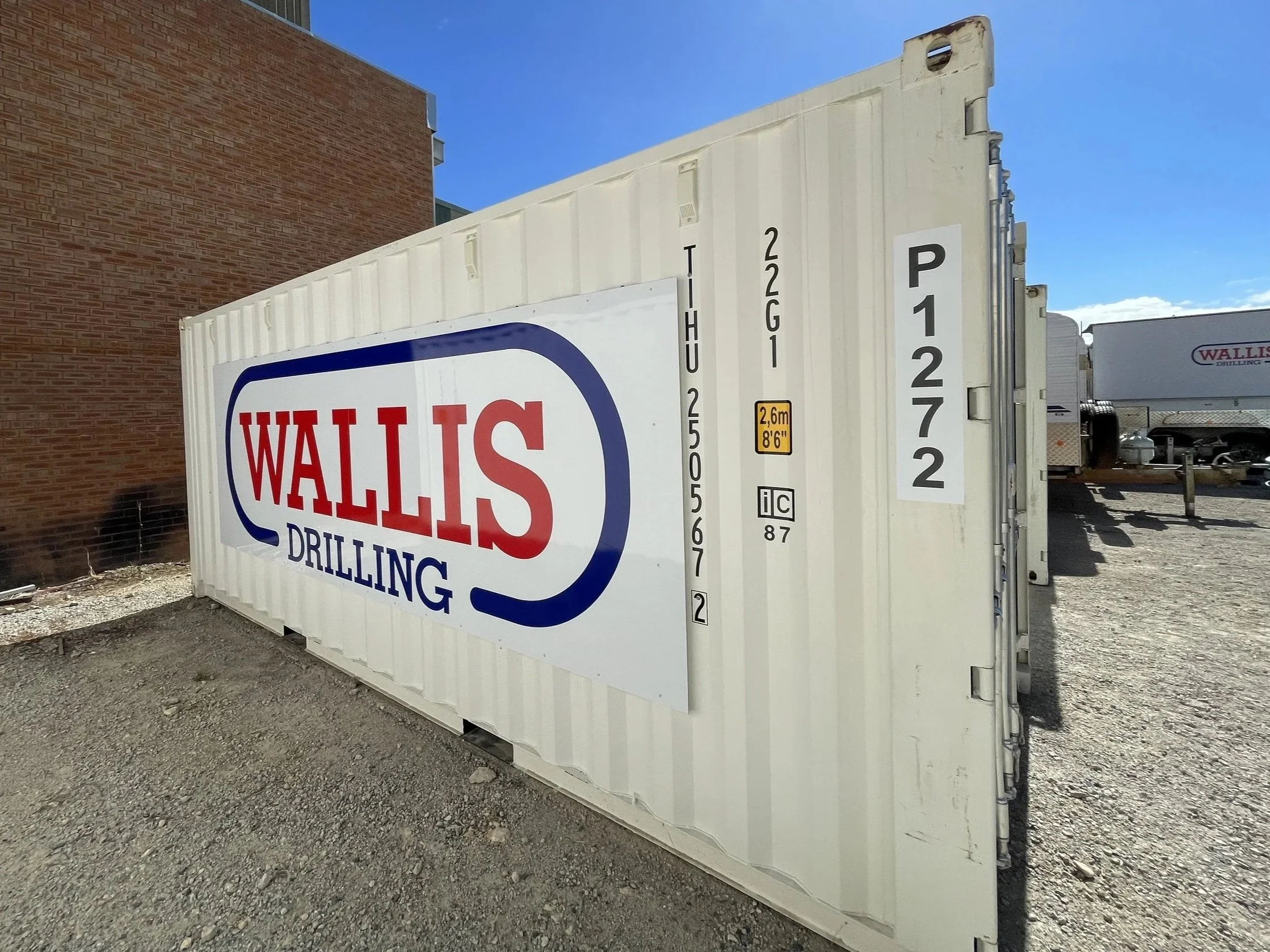 A white shipping container with a large wallis drilling signage - industrial branding