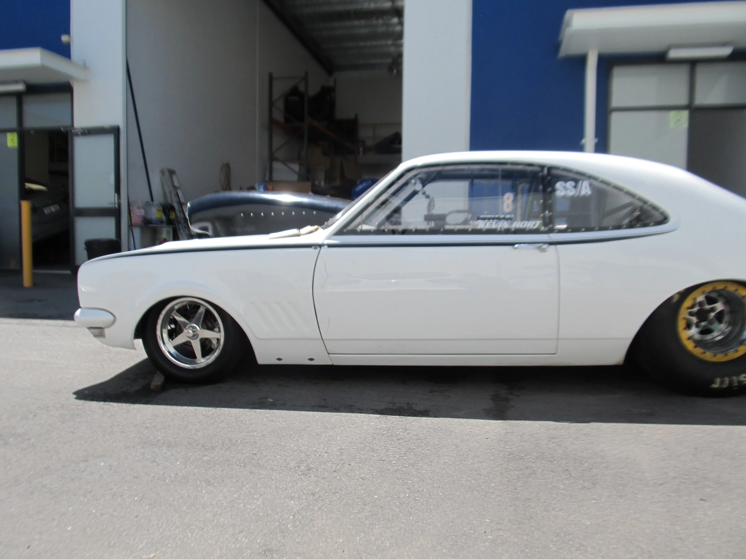 White vintage drag racing car with big semi slicks and pin striping decals