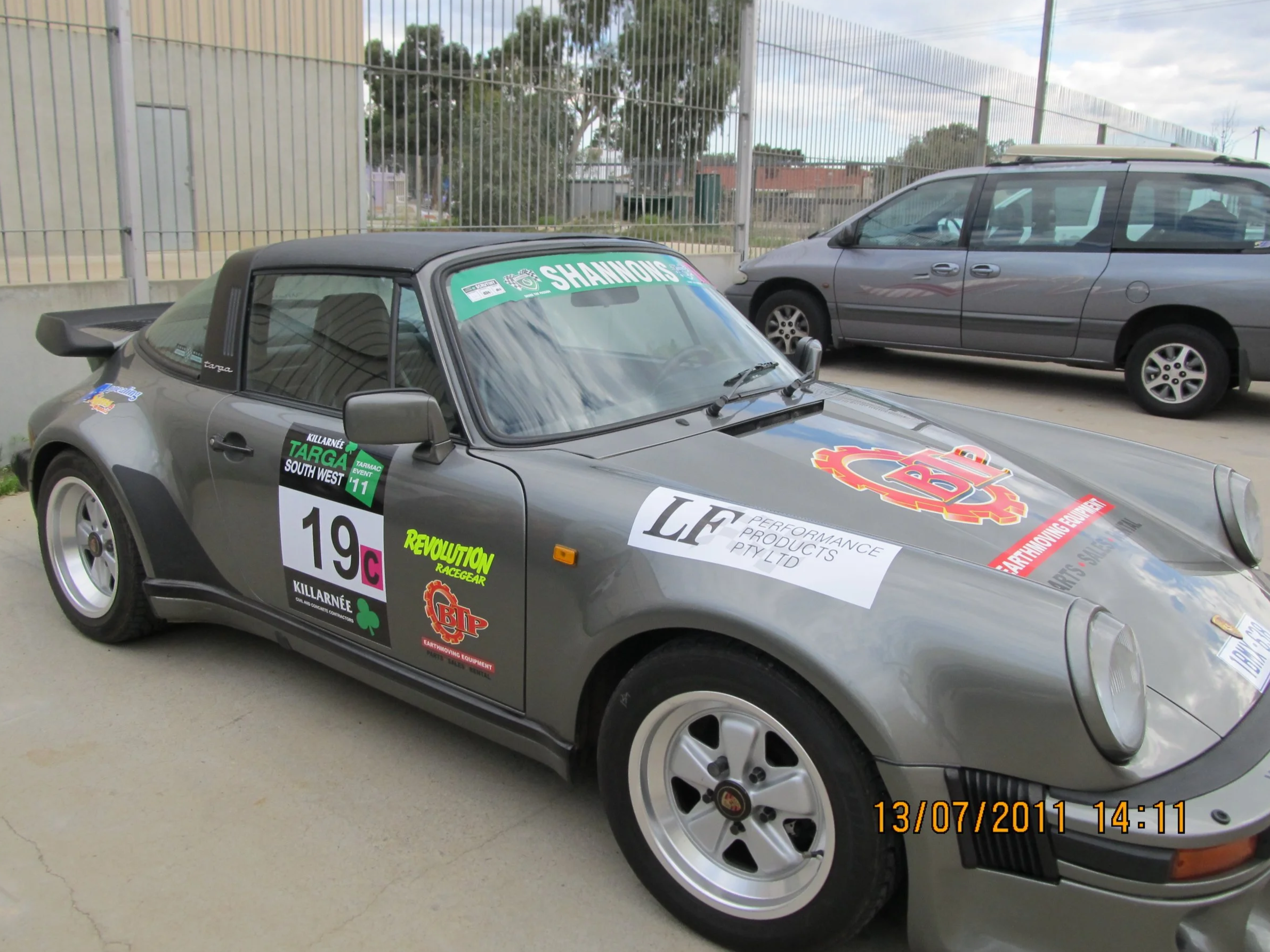 A gray Porsche 911 Targa with Targa West and racing sponsor decals.