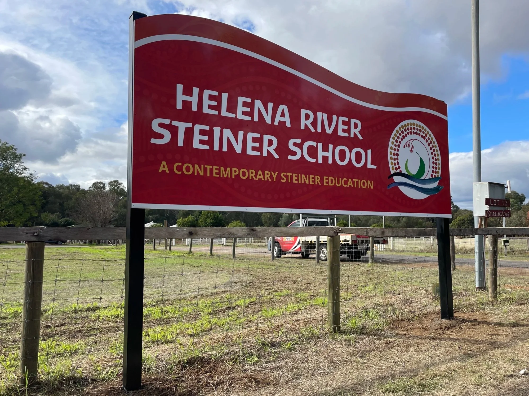 Large red sign with white text reading "Helena River Steiner School" and a subtitle "A Contemporary Steiner Education" in Hazelmere WA 6055. Hazelmere Road Signage. Hazelmere School Signage. Hazelmere Education Signage. Perth School Signs.
