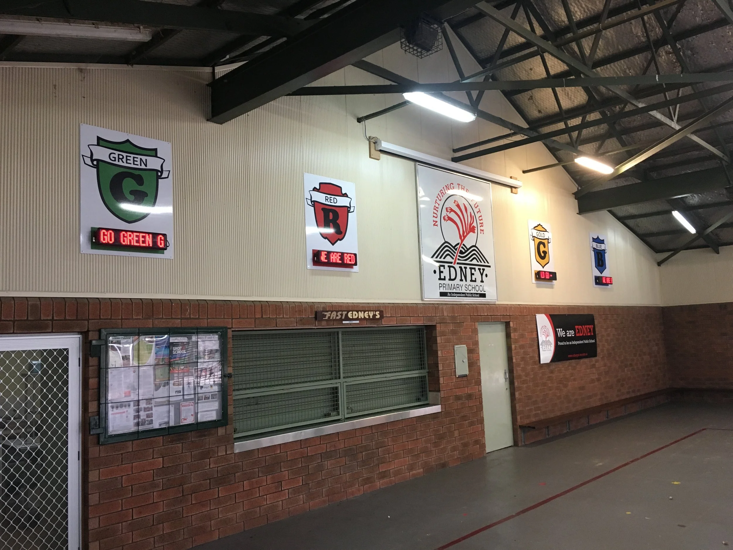 A school sports hall with sports signage and Basketball scoreboards. Education signage