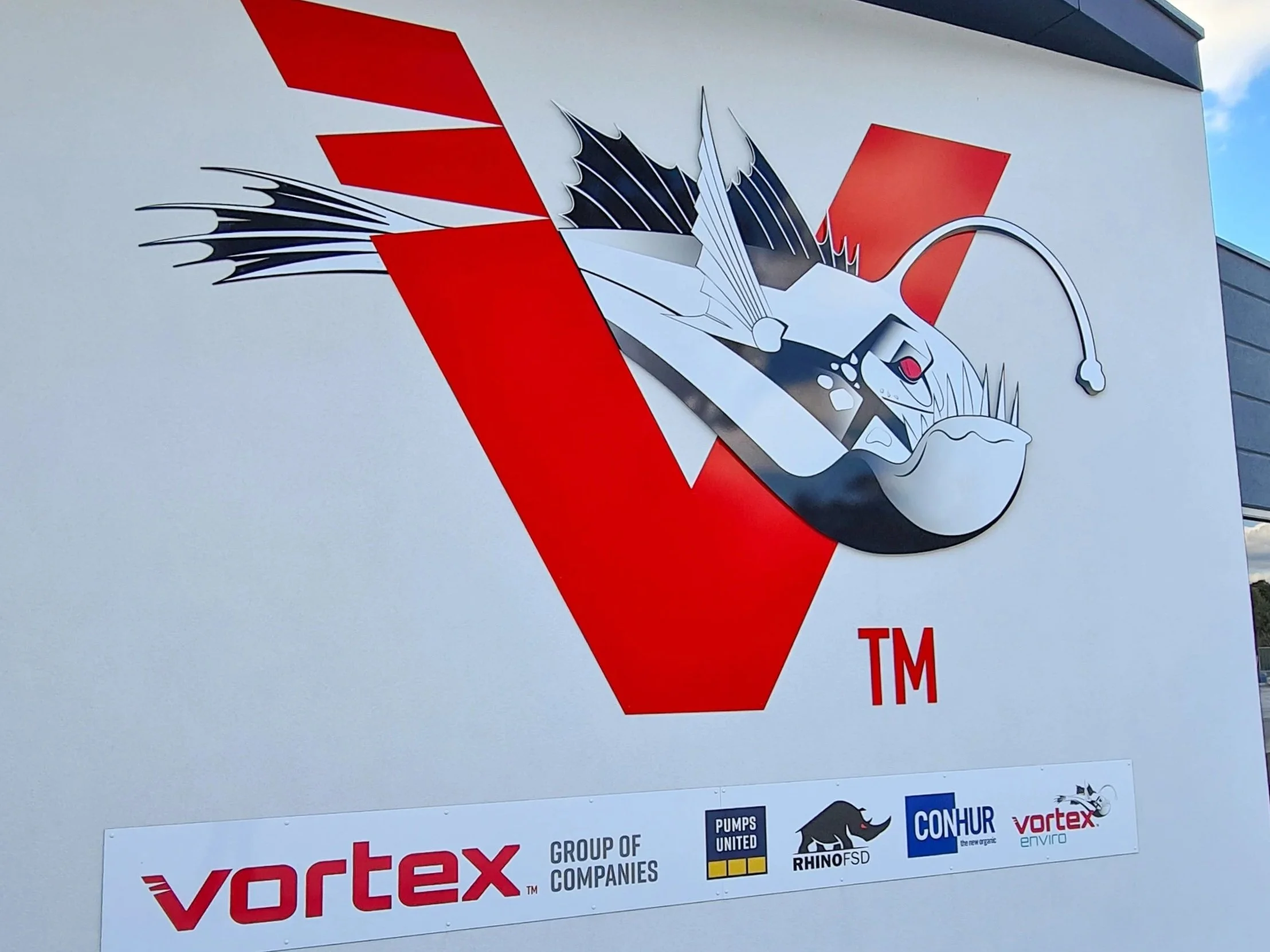 Sign with a stylized logo of a deep sea fish and Vortex logo. The bottom part of the sign shows logos of related companies, including Vortex, Rhino-FSD, CONHUR, and Pumps United.
