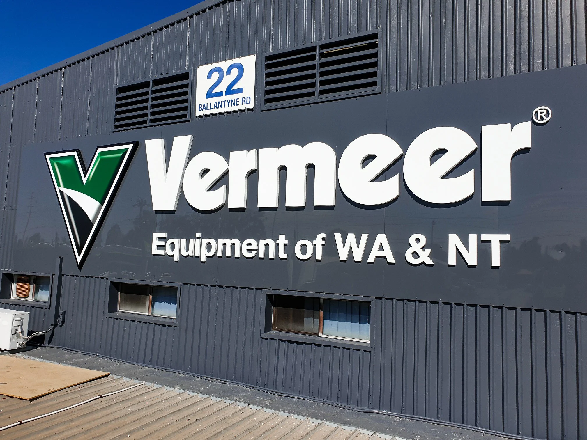 Photo of a commercial building with a 3D sign that says "Vermeer" and an address sign that reads "22 Ballantyne Rd."  Business and commercial signage and branding for Vermeer Equipment