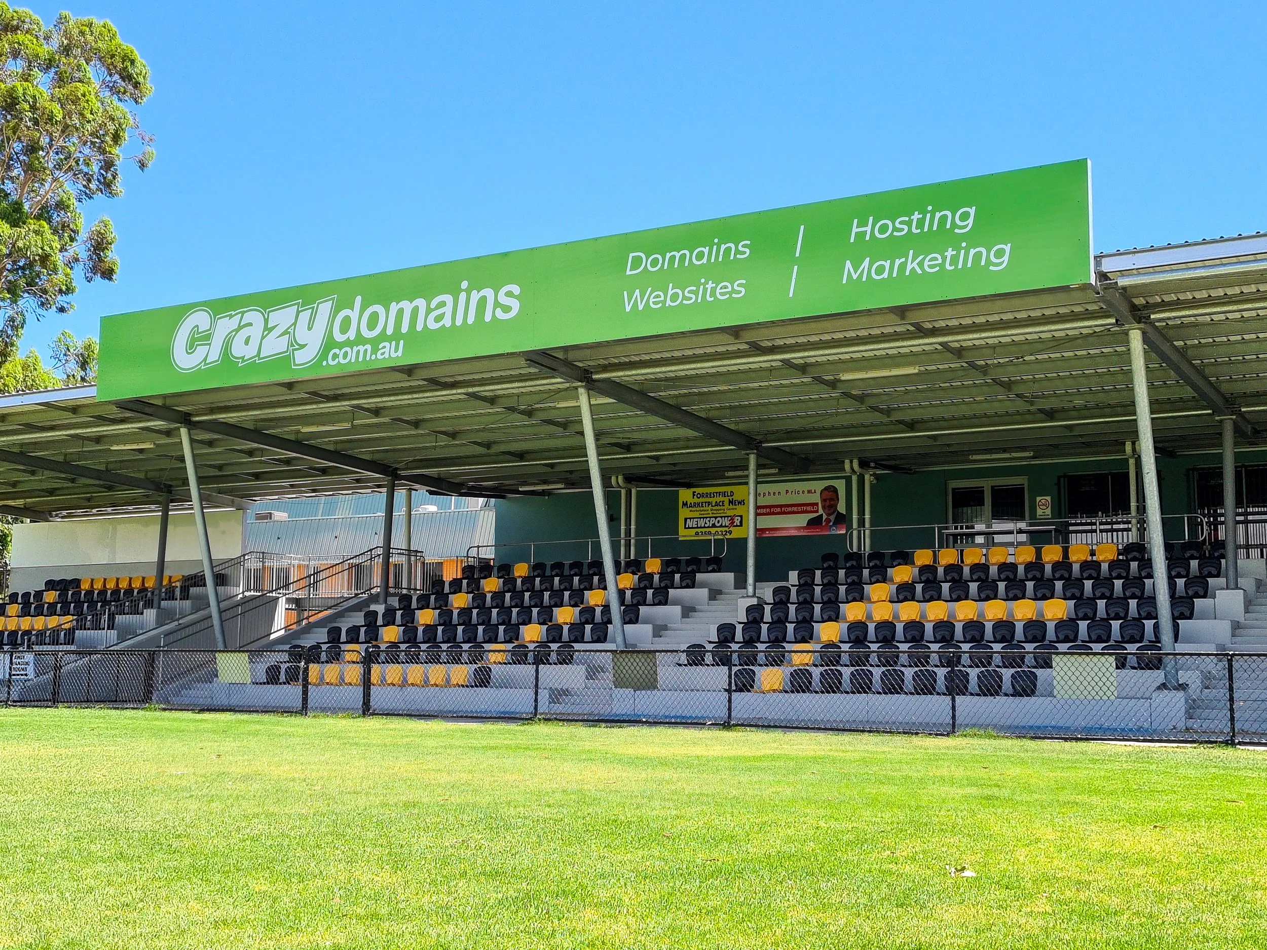 A soccer football stadium with a large sponsor sign above reading Crazy Domains - Fascia signage