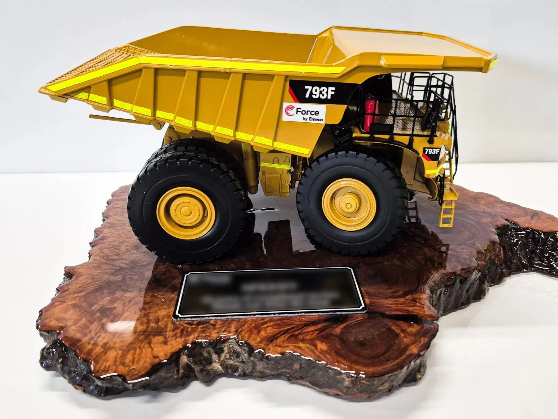 A scale model of a yellow dump truck with black details, mounted on a polished wooden base with a black plaque. Custom mining gifts