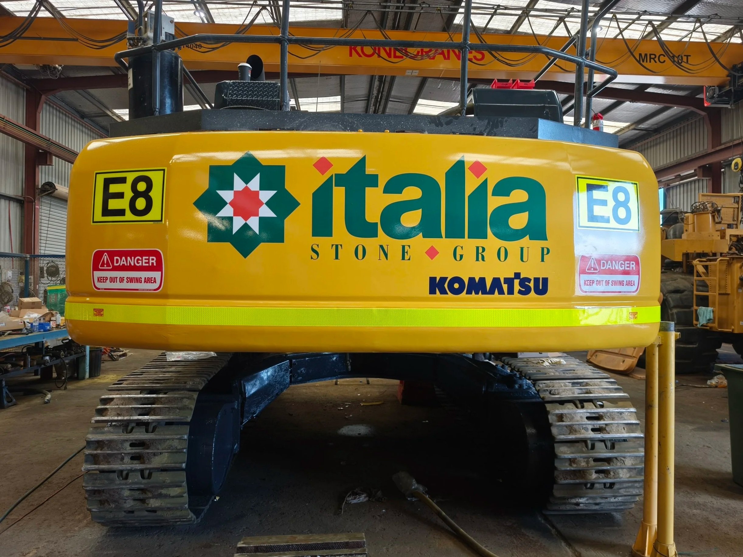 A yellow mining machine with logos and labels including 'Itala Stone Group,' 'Komatsu,' and Asset Number 'E8. with High Visibility DG3 striping