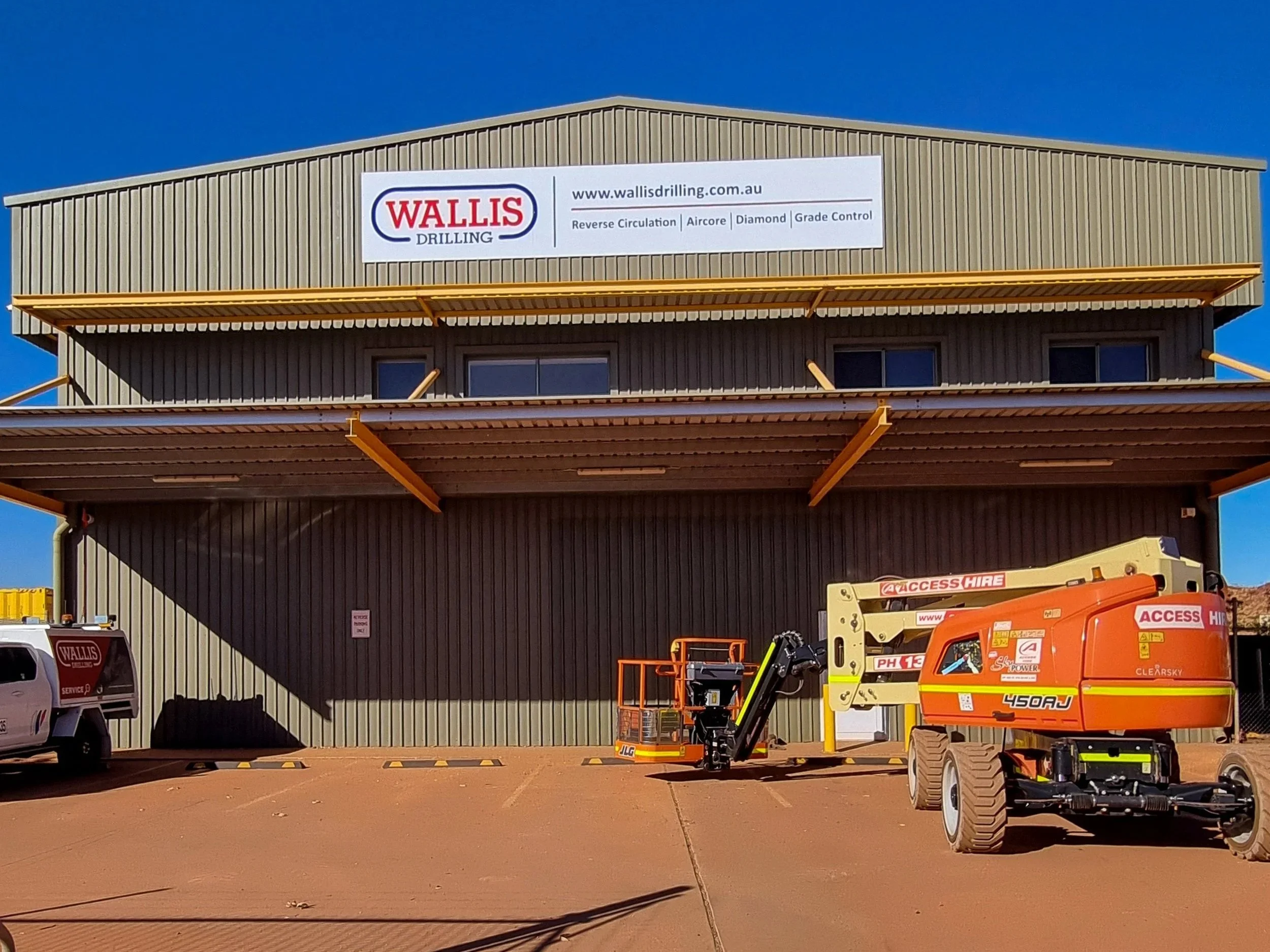 A large industrial building with a fascia sign for Wallis Drilling. Business Signage and regional mining town Newman