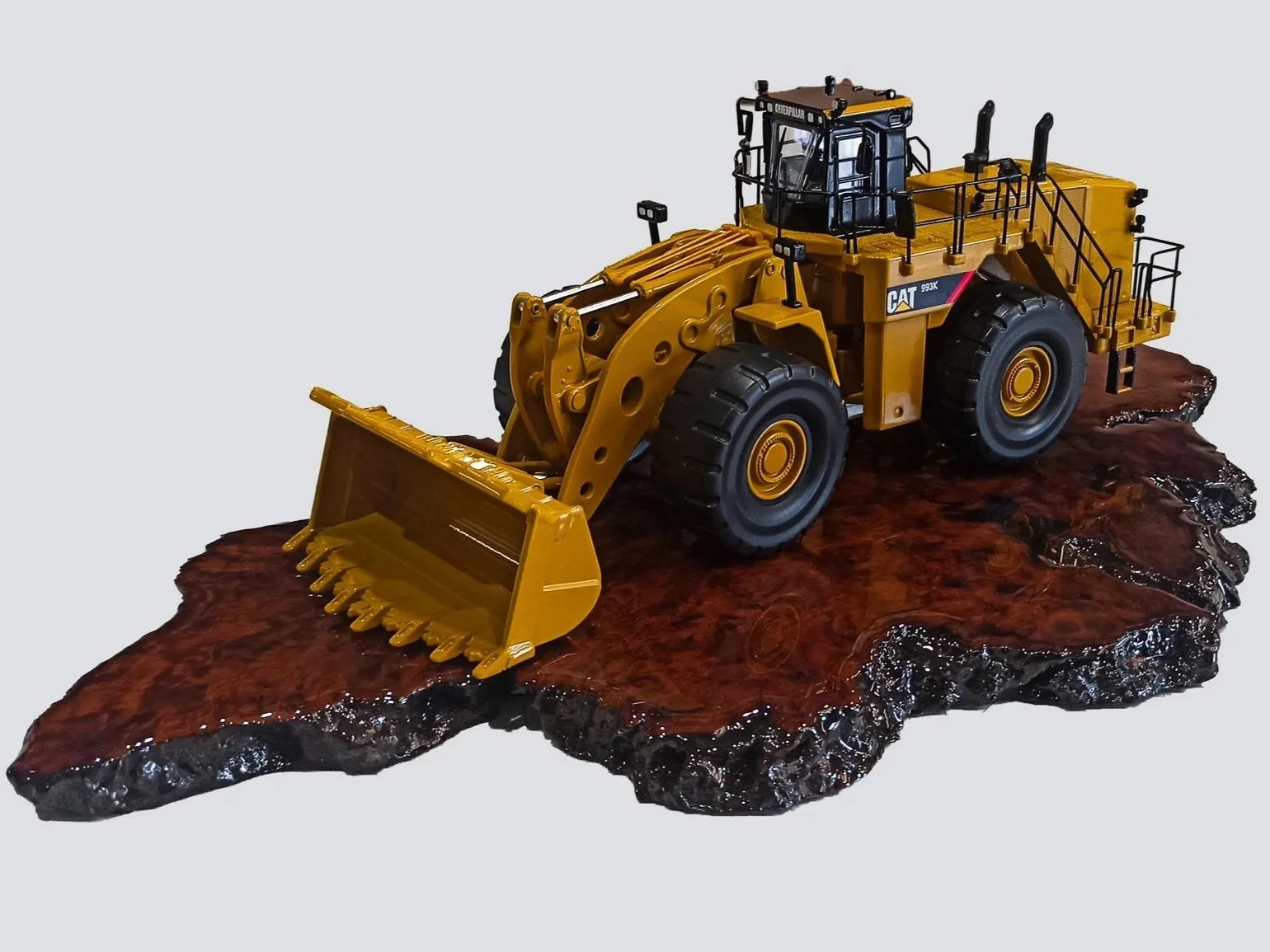 A small scale model of a yellow Caterpillar bulldozer on a wooden base. Custom mining gifts