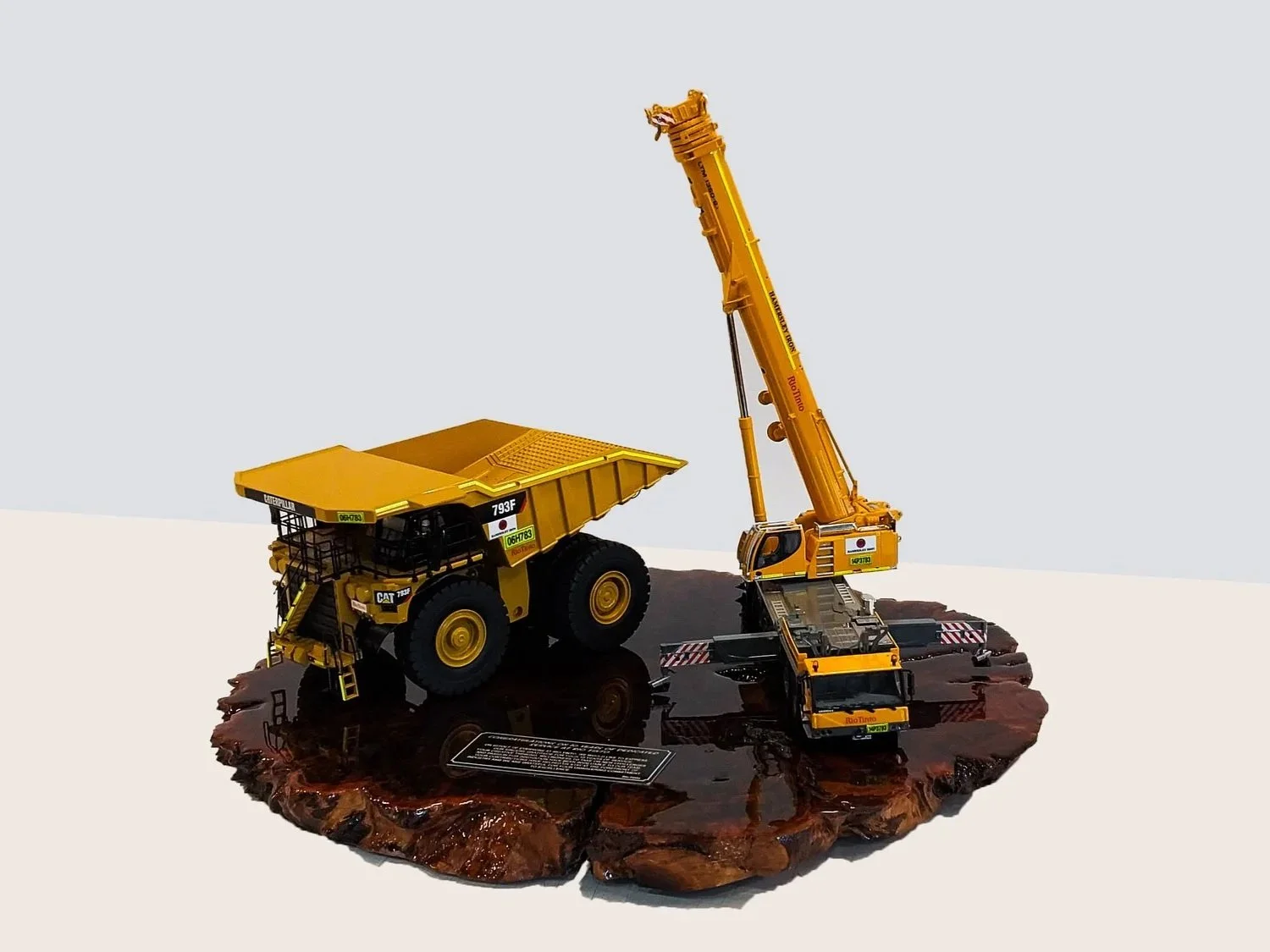 Scale model of a yellow dump truck with a crane, displayed on a wooden base. Custom mining gifts