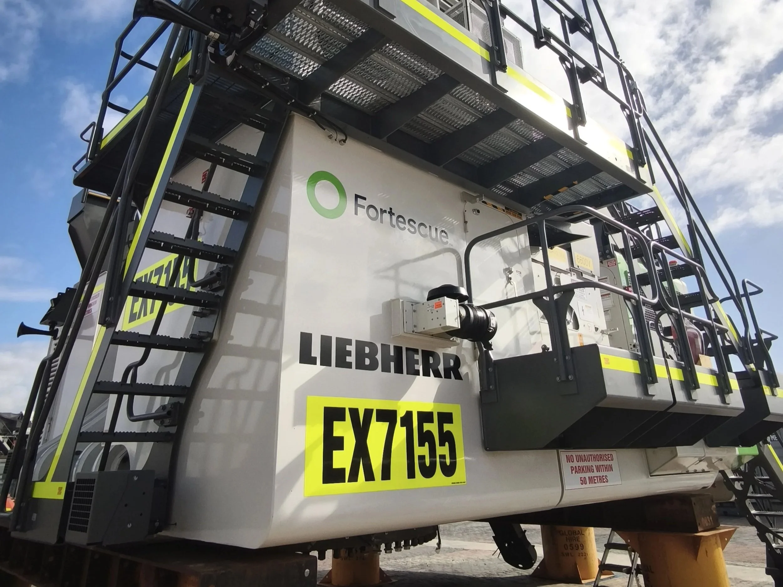 Close-up of a large mining machine labelled 'LIEBHERR' and 'Fortescue' with yellow safety markings and Asset Number. Industrial Mining Machinery Signage