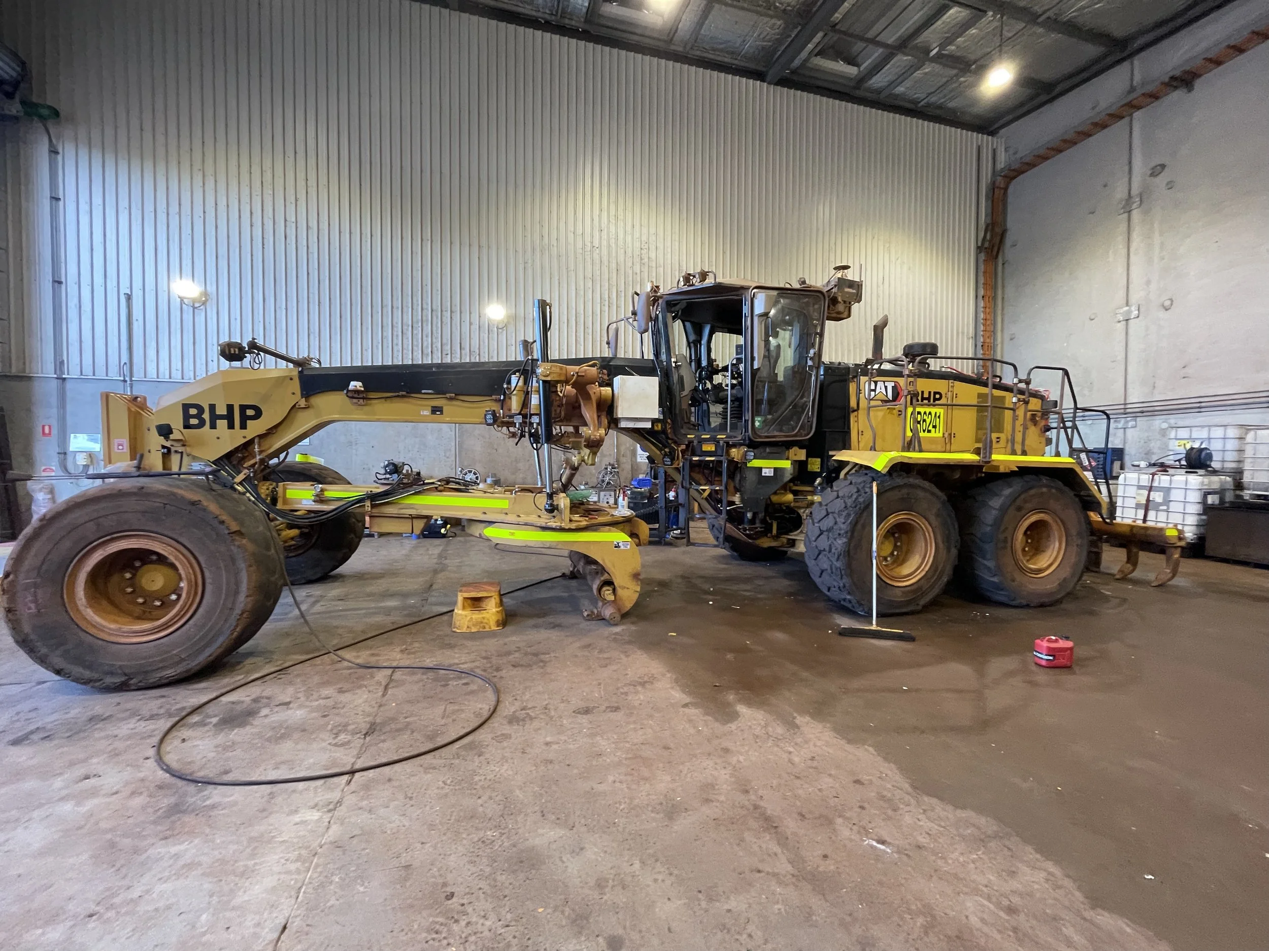 Yellow Caterpillar Machine with high-visibility DG3 striping and Asset Numbers.