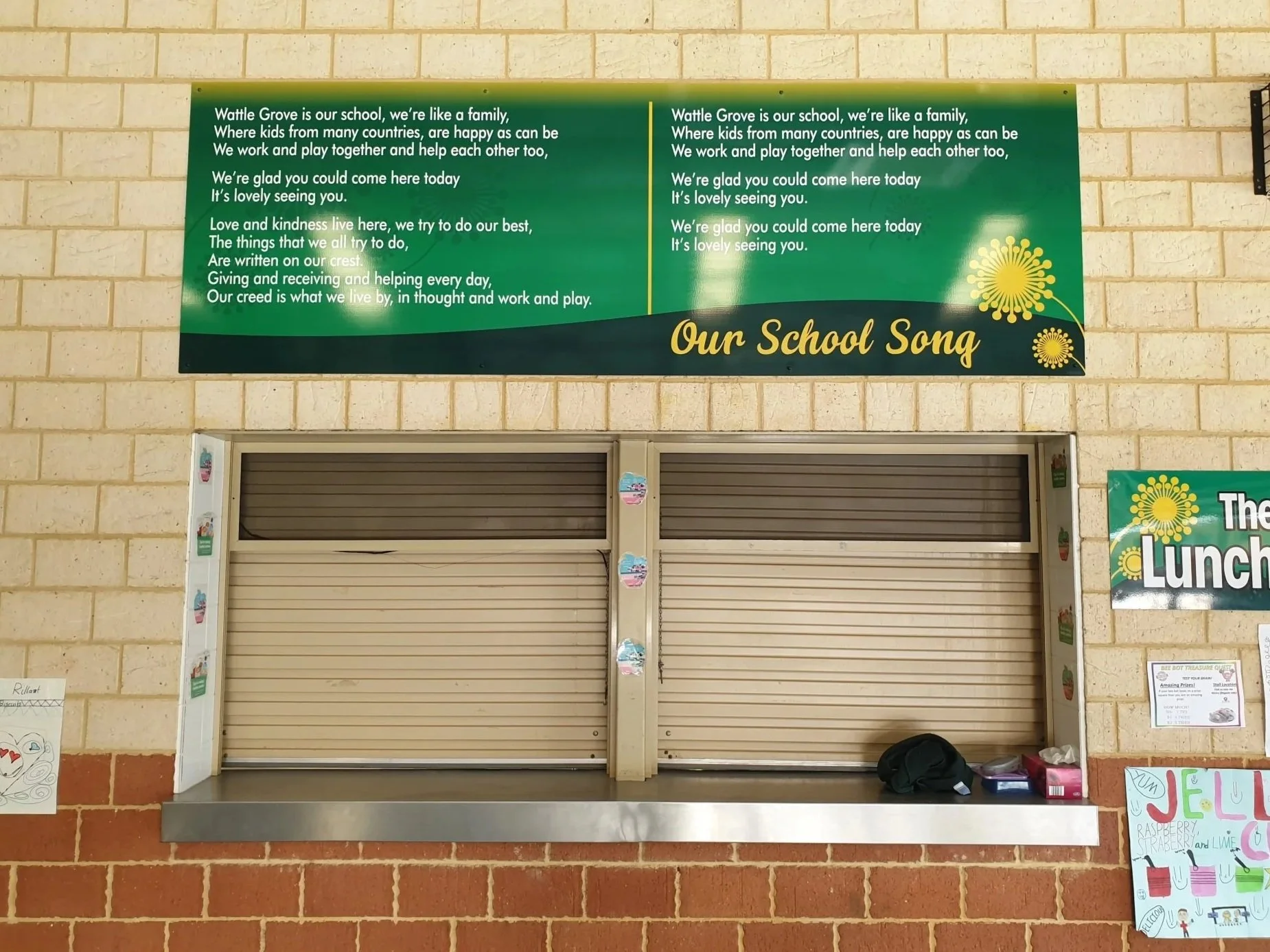 A green sign with a song and a list of school rules hangs above a closed school cafeteria window. Cafeteria Signage Perth. Indoor Signage Perth. Education Signage Perth. School Signage Perth