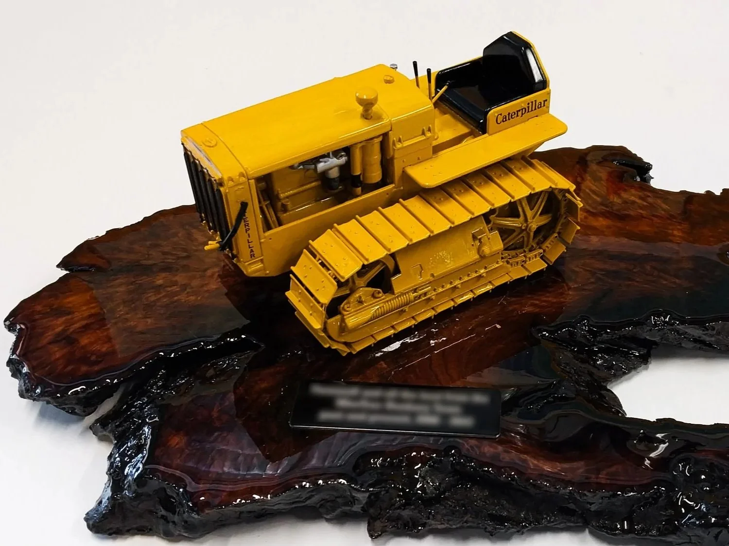 A detailed yellow Caterpillar bulldozer scale model displayed on a polished wooden base. Custom mining gifts