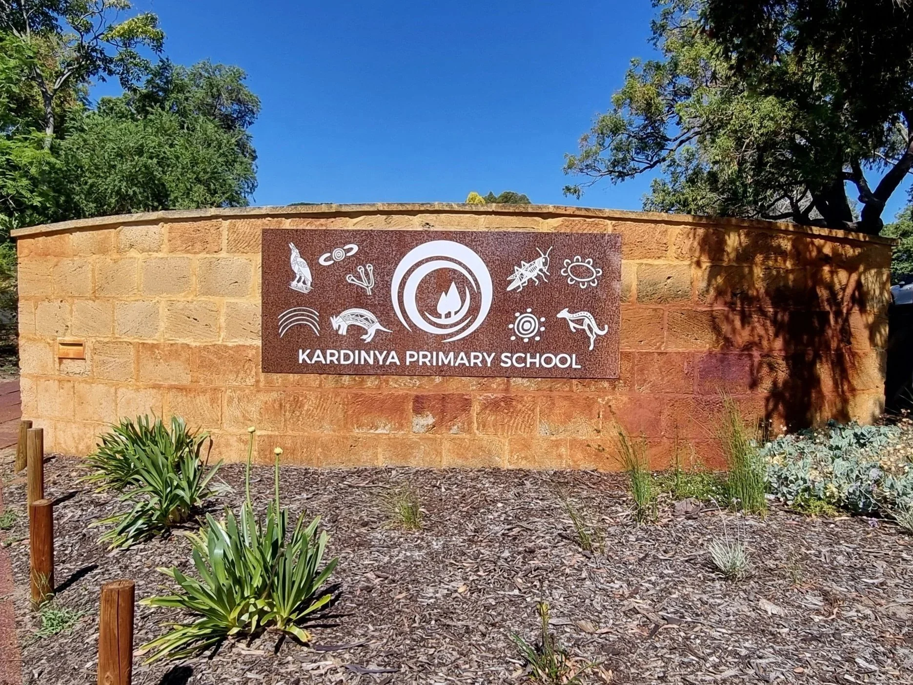 Sign for Kardinya Primary School on a brick wall with indigenous artwork in Kardinya. Entrance Signage Ochiltree Way, Kardinya WA 6163. Custom Metal Signage Kardinya. Custom Cut Metal Signage Perth. Kardinya Rustic Signs. Perth Rustic Signs.