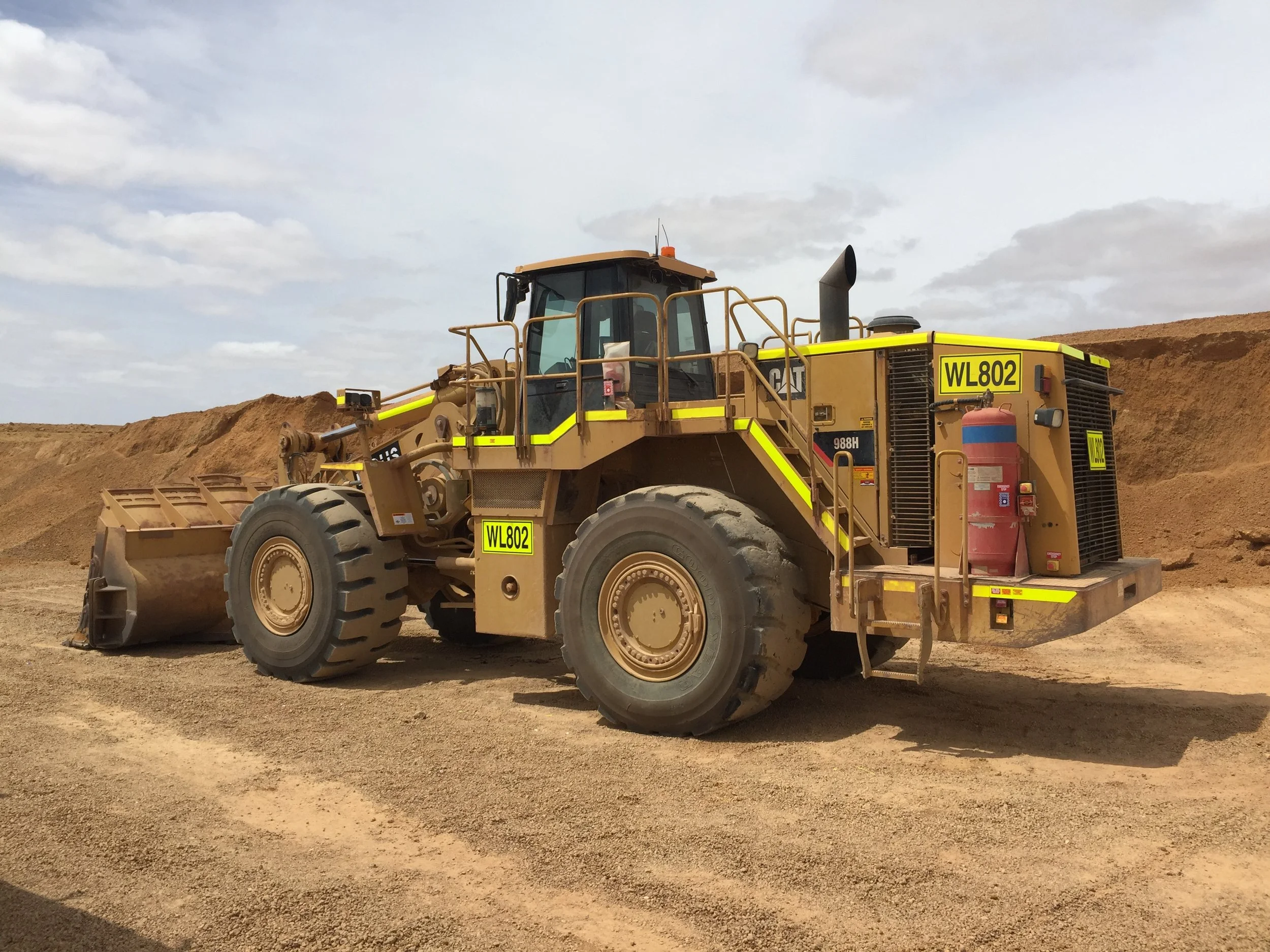 A large yellow Caterpillar bulldozer with high-visibility DG3 striping and Asset Numbers.