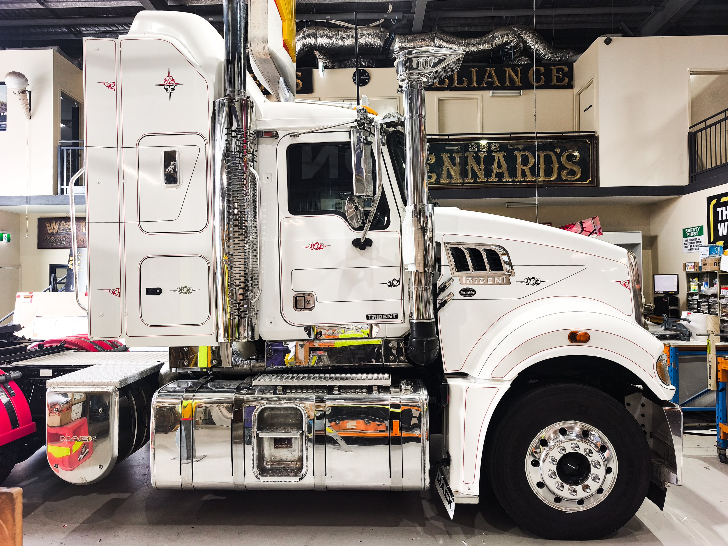 A white semi-truck fitted with old school pin striping and scroll decals. Personalised vehicle decals