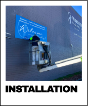 Person installing a wall mounted sign using a portable lift