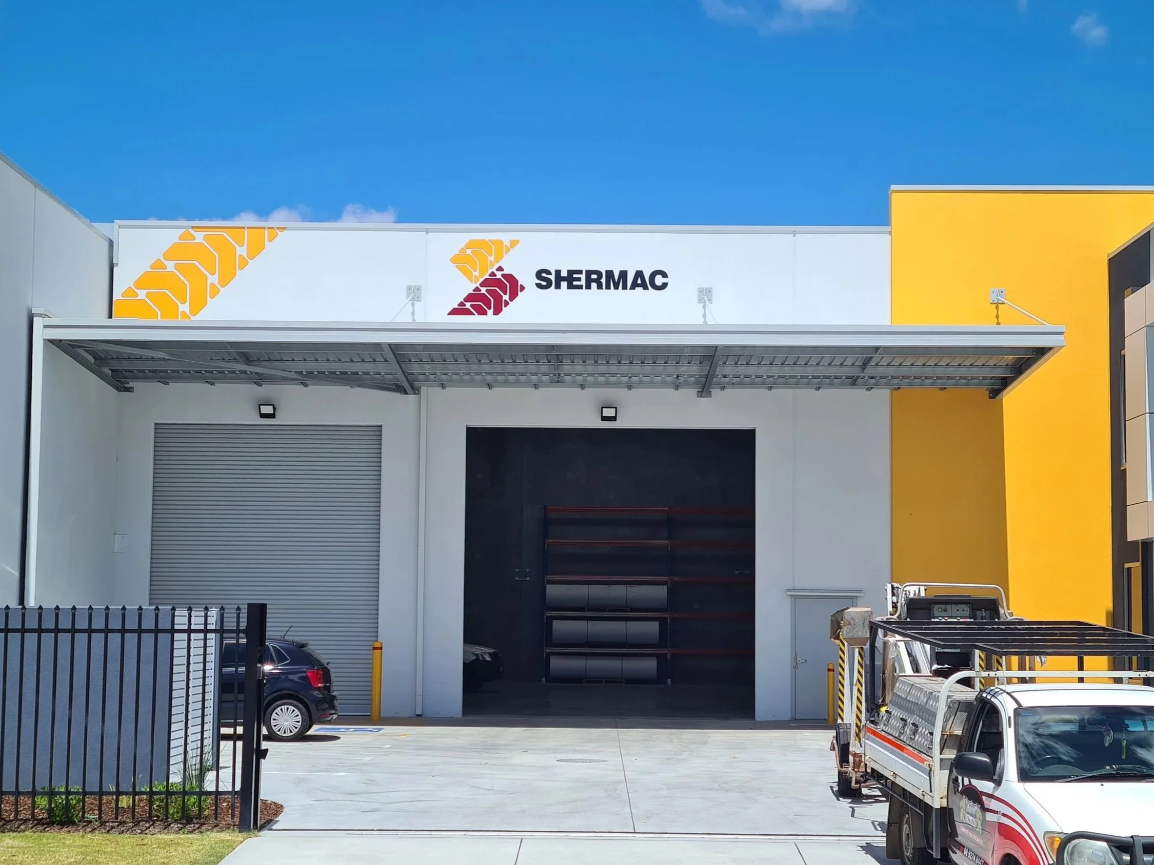 Front of a commercial building with a sign that reads 'SHERMAC'. Commercial industrial signage