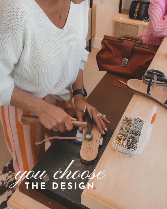Person using a hammer to assemble a leather sandal with a padded insole on a workbench surrounded by tools and supplies.
