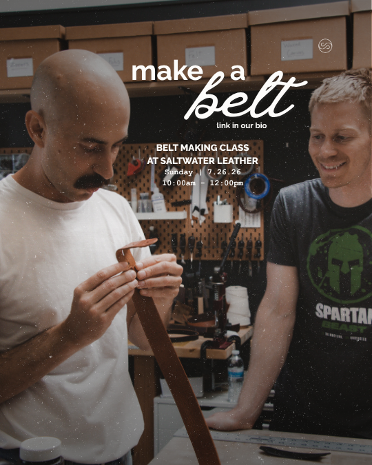 Two men in a leather workshop making a belt. One man is inspecting the belt strap, and the other is smiling. The workshop has tools and materials for leather crafting. Text on the image promotes a belt making class at Saltwater Leather.