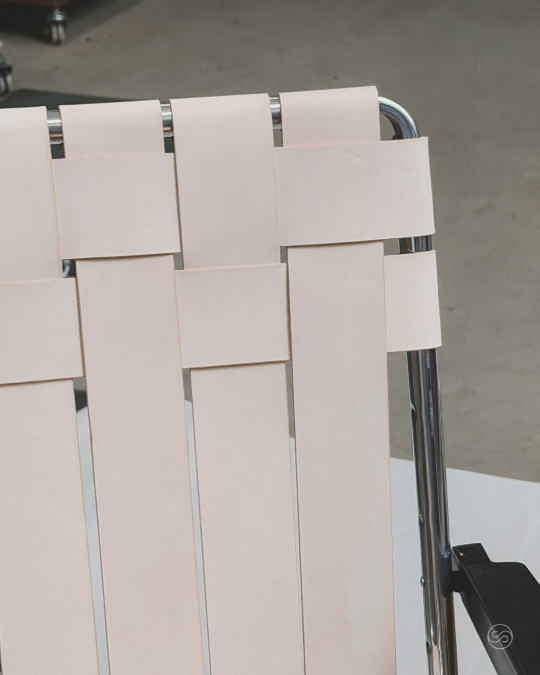 Part of a shopping cart with a cream-colored woven plastic design in an indoor or parking lot setting.