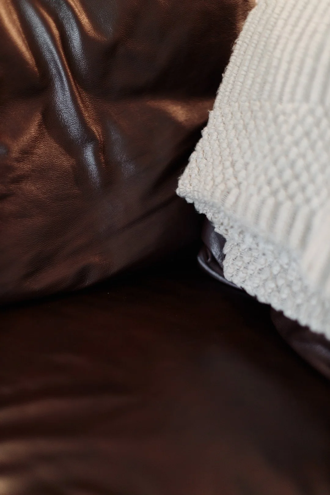 Close-up of a brown leather surface and a cream-colored textured fabric surface.