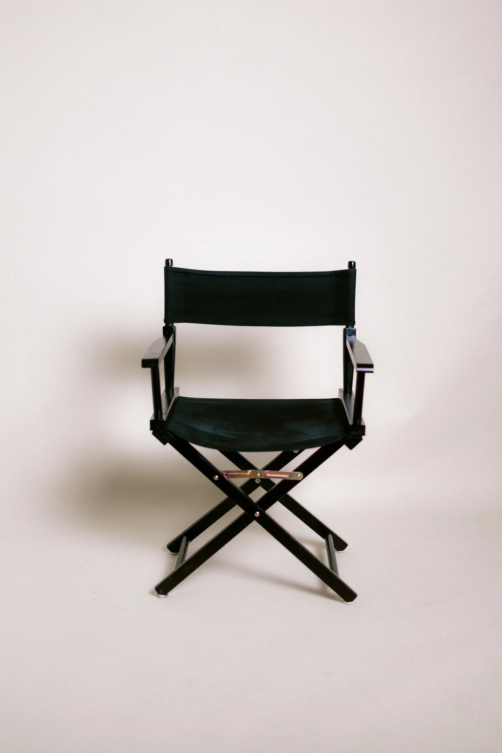 A black director's chair with a metal frame against a plain white background.