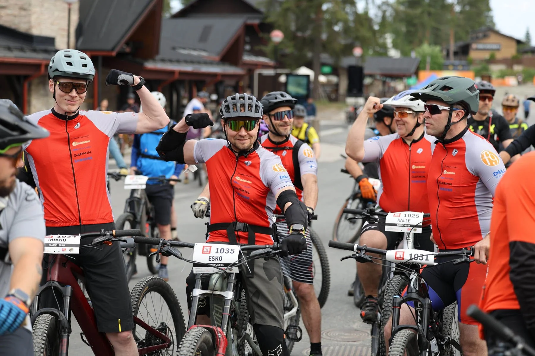 Ryhmä pyöräilijöitä juhlii ennen kilpailua, kaikki ovat pukeutuneet puna-mustaan ja heillä on kypärät ja suojalasit.