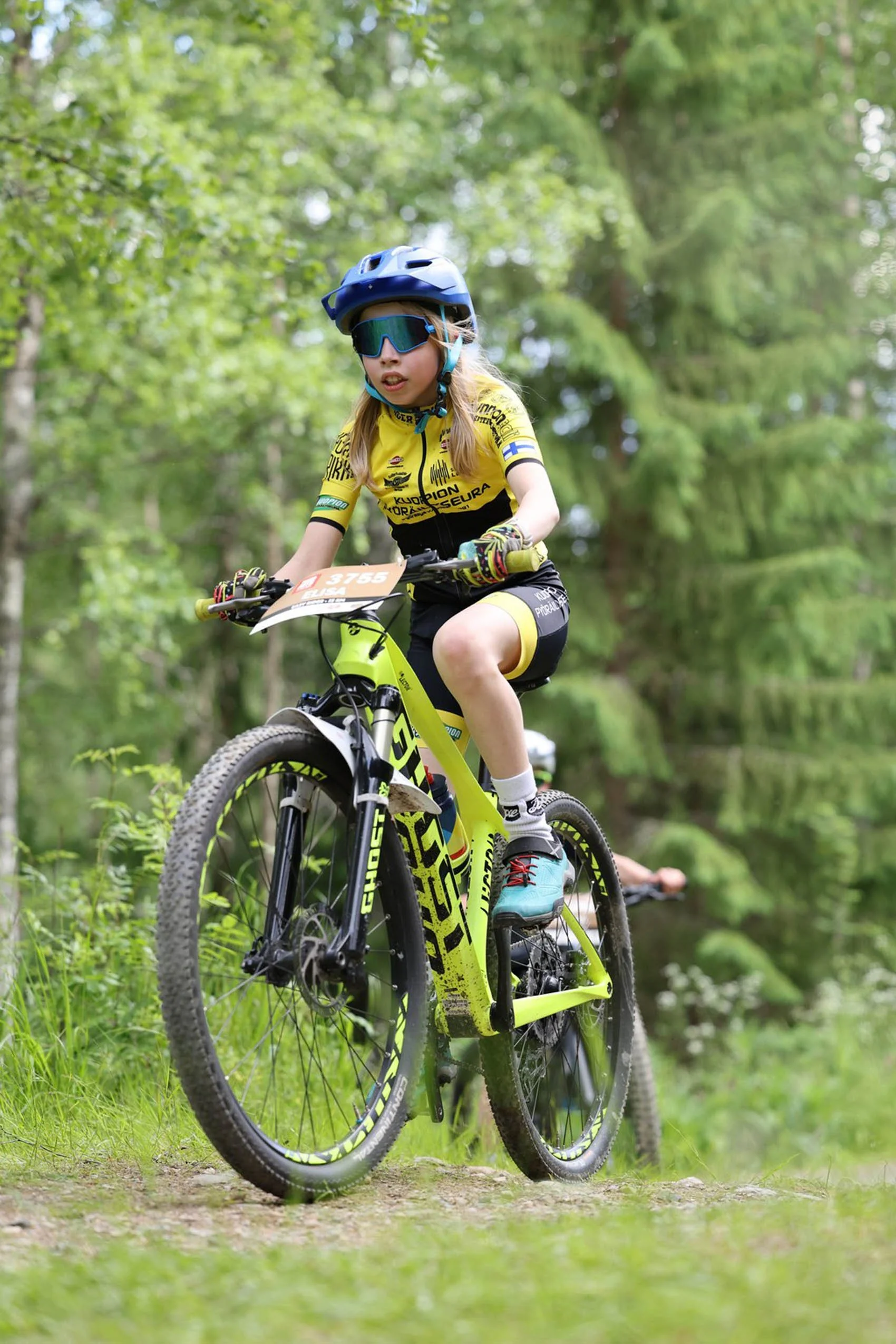 Lapsi pyöräilee maastopyörällä metsässä.