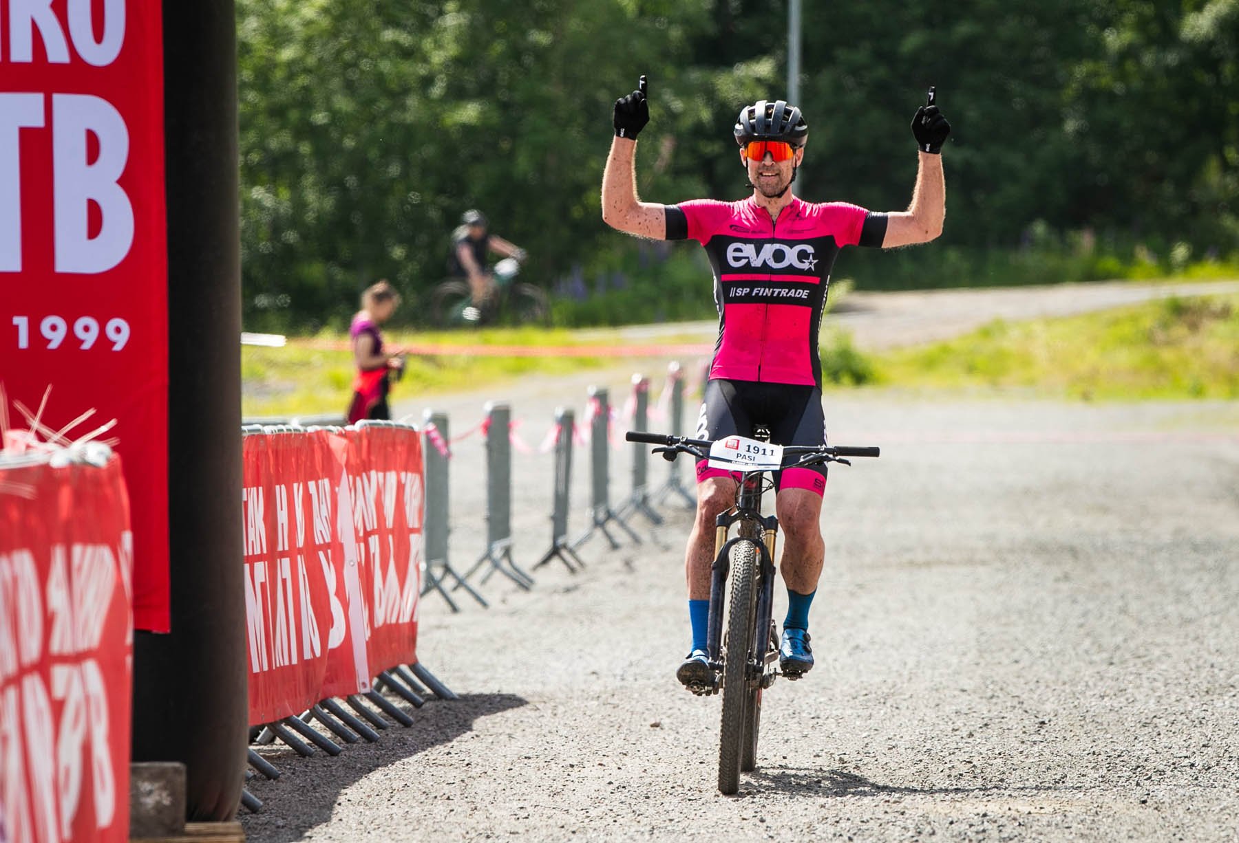 Mies onnistuneen kilpailusuorituksen jälkeen. Hän iloitsee ja osoittaa voittoa kahdella sormella.