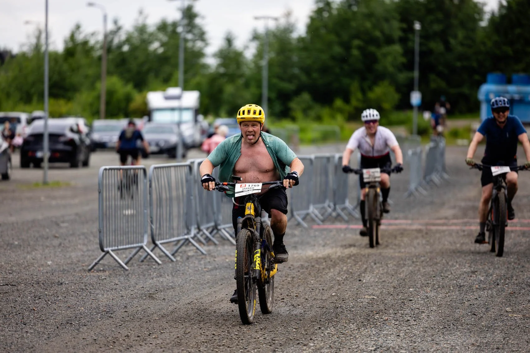 Ihmisiä pyöräilee kohti maalia. Yhdellä on paita auki. Kaikilla on kypärät.