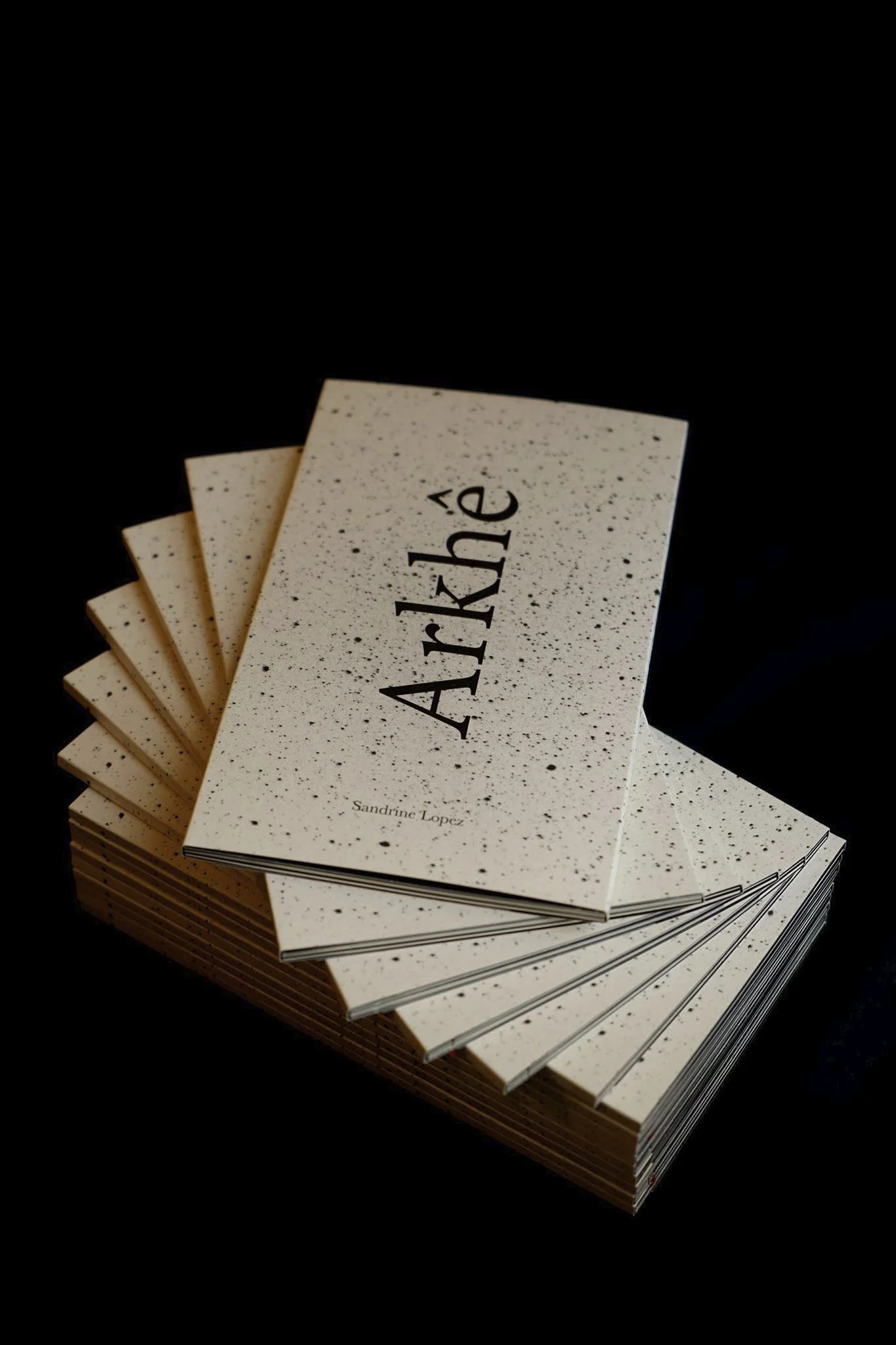 Cartes de visite empilées avec la marque 'Arké' et le nom 'Sandrine Lopez' sur un fond noir.
