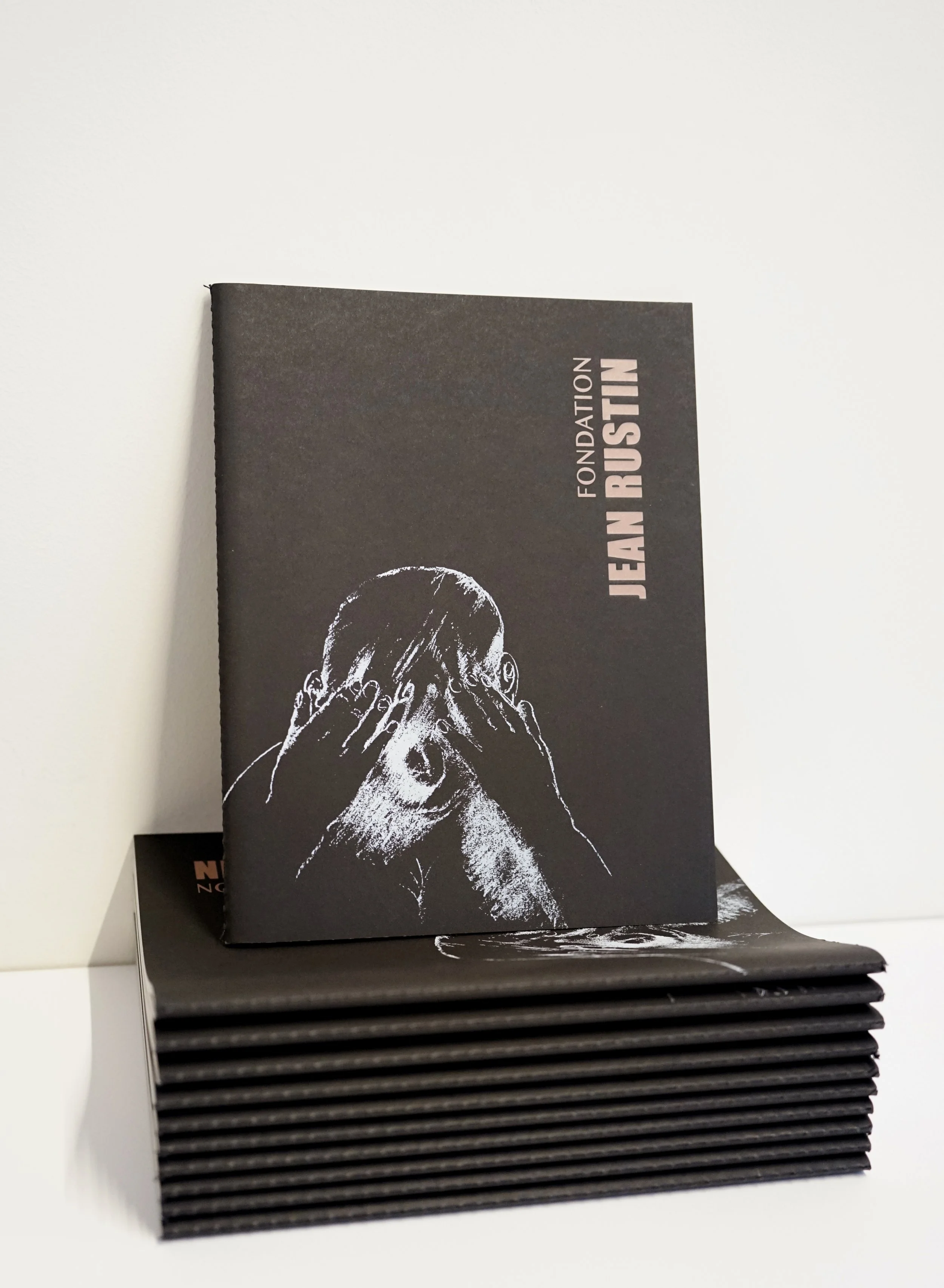 Livres noirs empilés avec une couverture illustrée d'une personne tenant ses mains sur son visage.