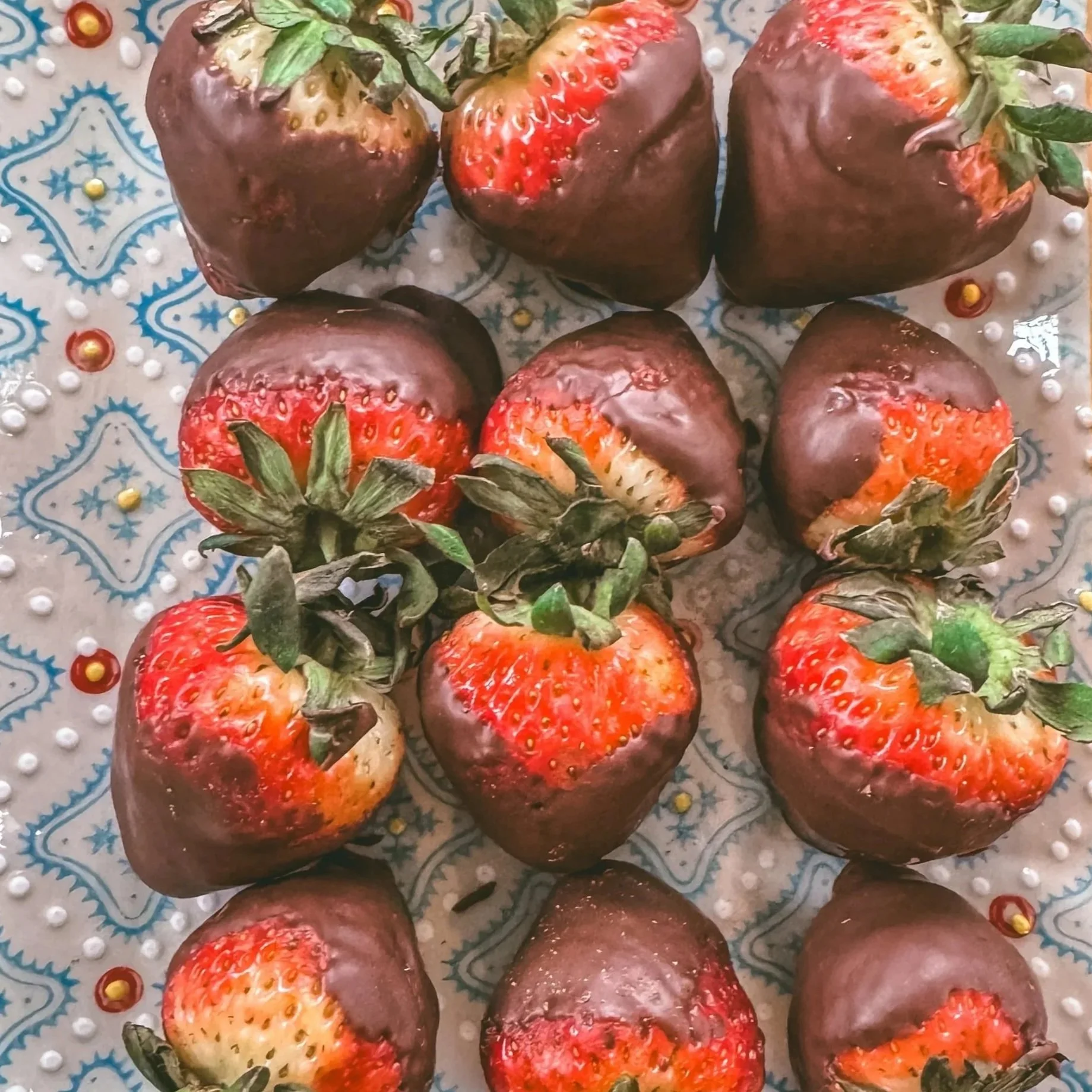 Strawberries half-dipped in chocolate on a decorative surface.