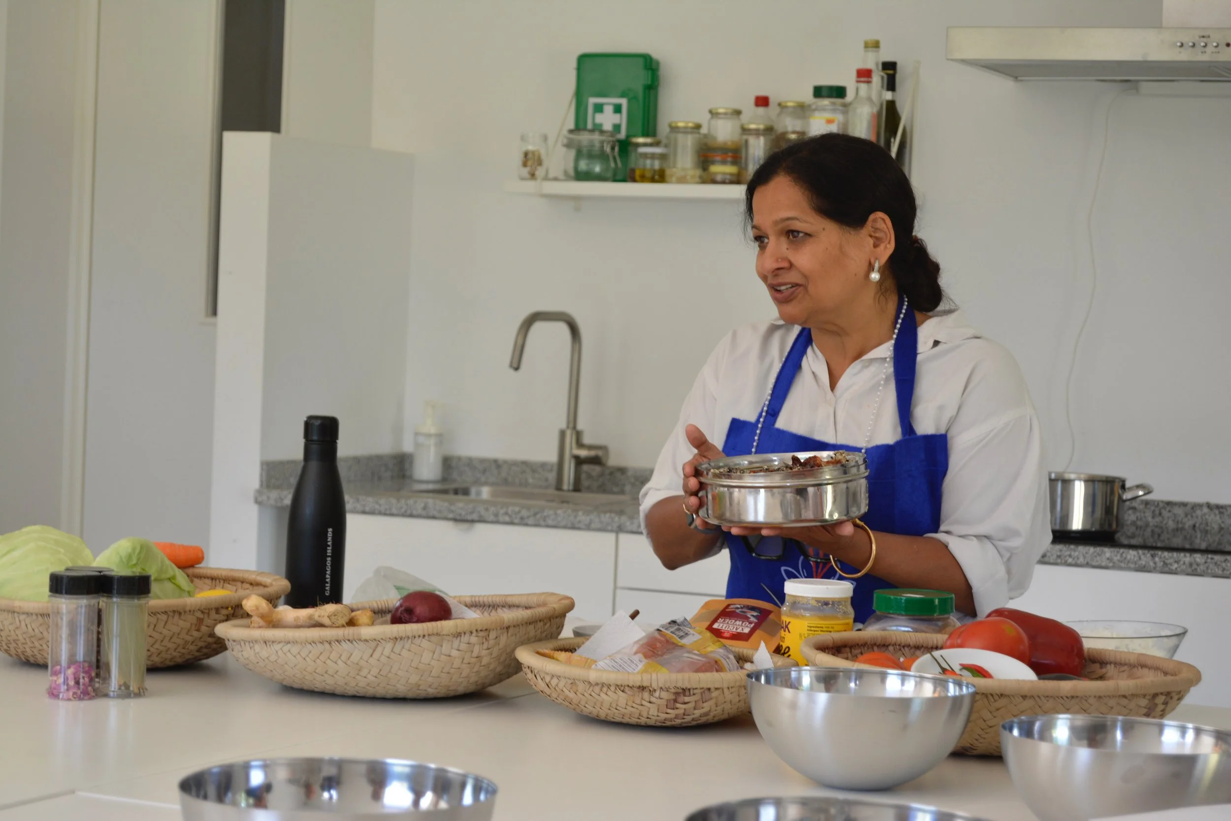 Chef Sarita Bhagwat demonstrating traditional Indian cooking techniques during a hands-on culinary class, teaching authentic Indian cuisine with fresh ingredients and regional recipes.