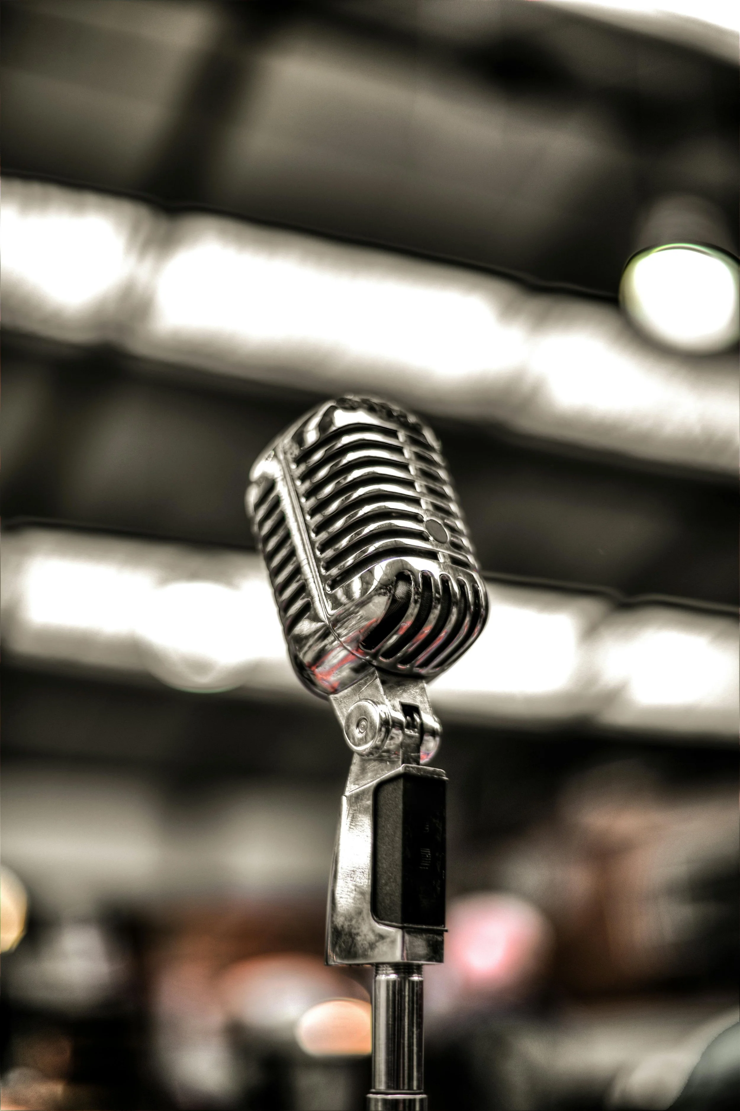 A vintage silver microphone with a grill design, mounted on a stand, indoors.