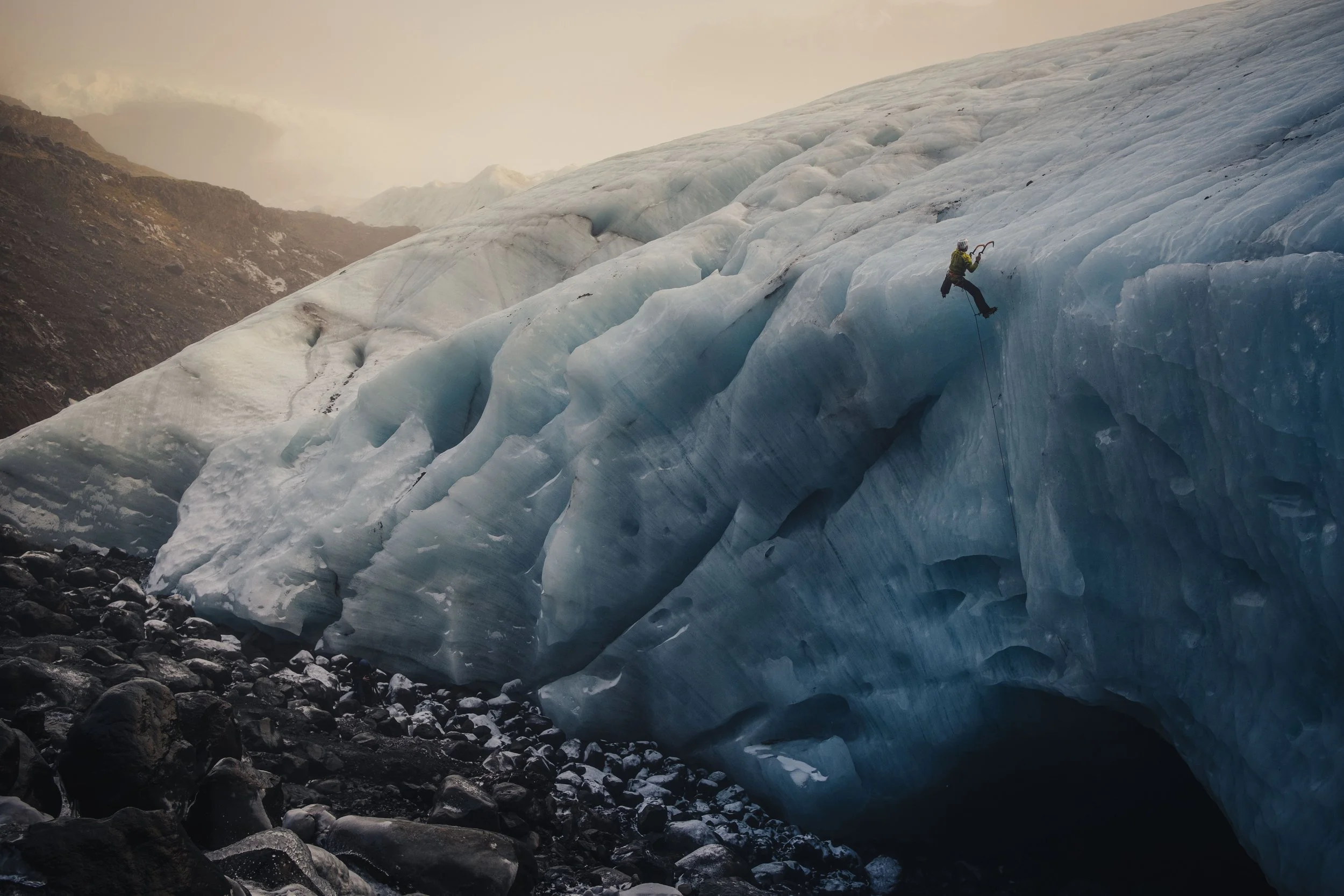 A person ice climbing on a glacier with mountain landscape in background