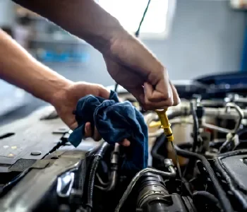 A person working on a car engine, using tools to make repairs or adjustments.
