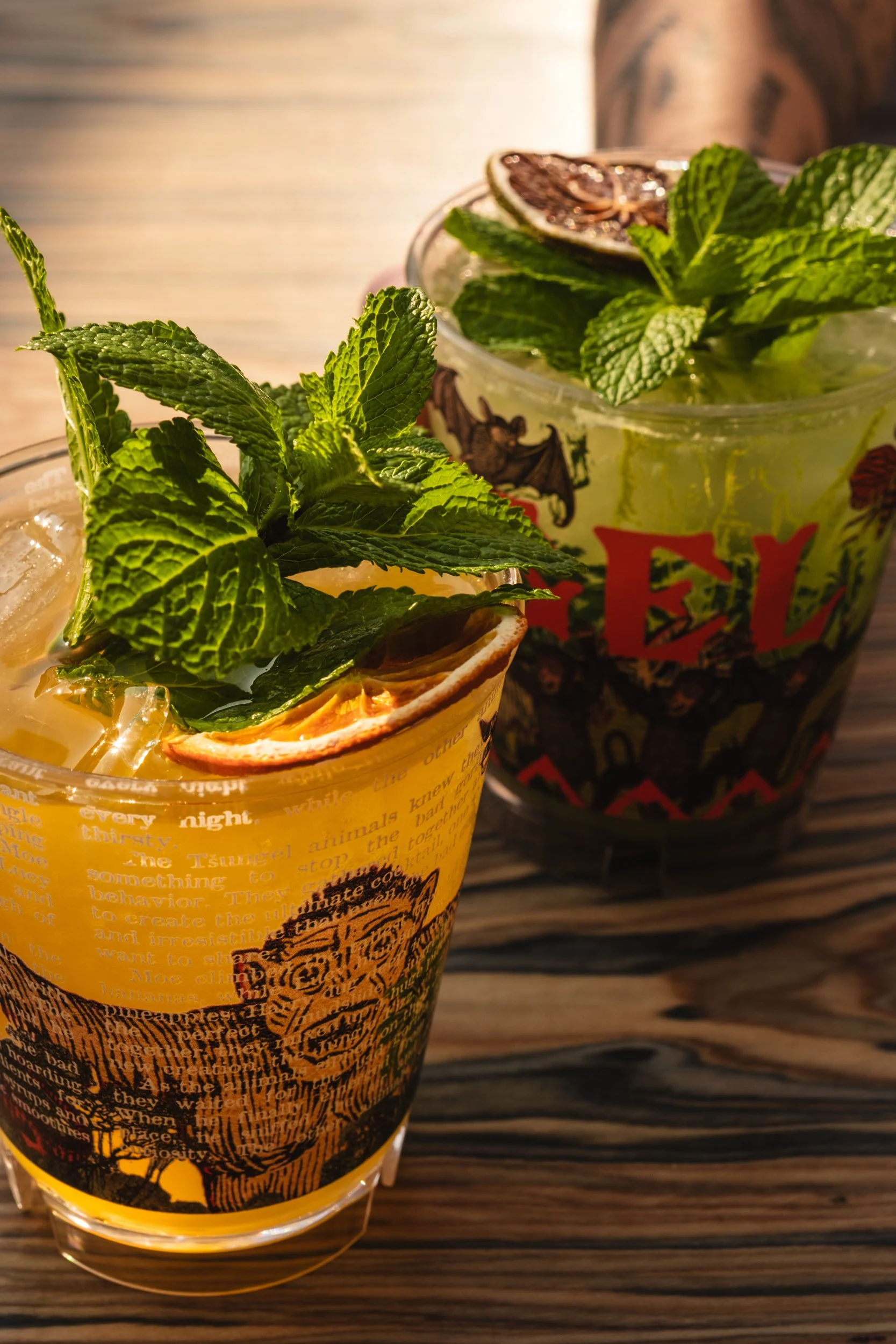 A glass containing a red beverage with ice and fresh green basil leaves on top.