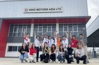 Group of people posing in front of a Hino Motors Asia Ltd. building.