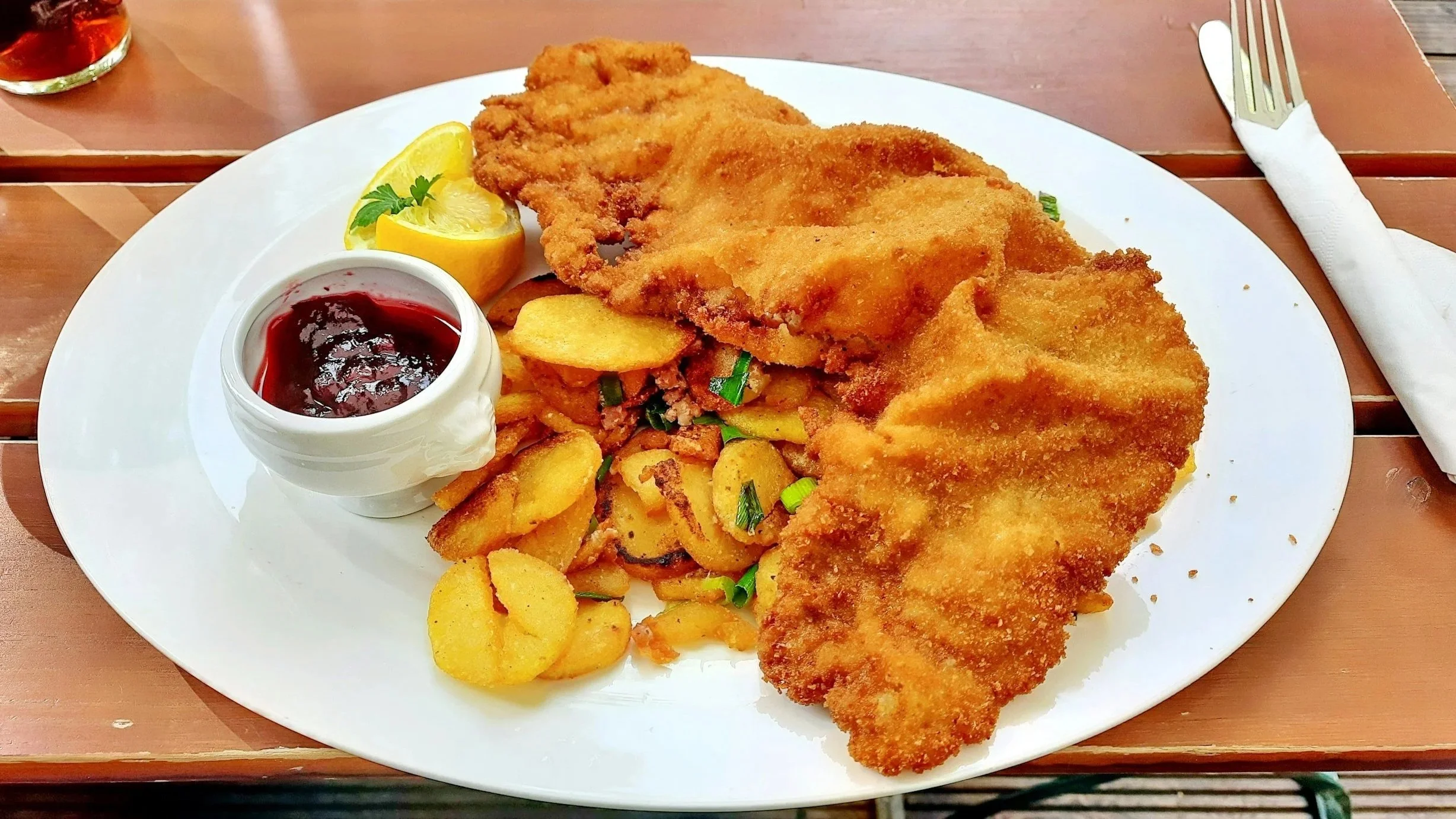 Kabeljaufilet mit Zitronenscheibe, Kartoffeln, Zwiebeln und Preiselbeeren auf weißem Teller