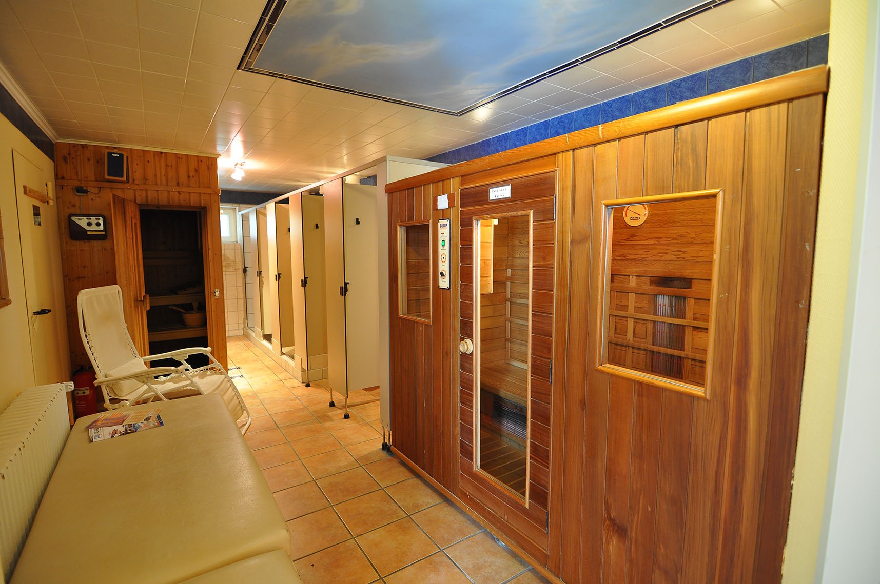 Sauna- und Umkleideraum mit Kabinen, Liege, Liegestuhl und Liege.