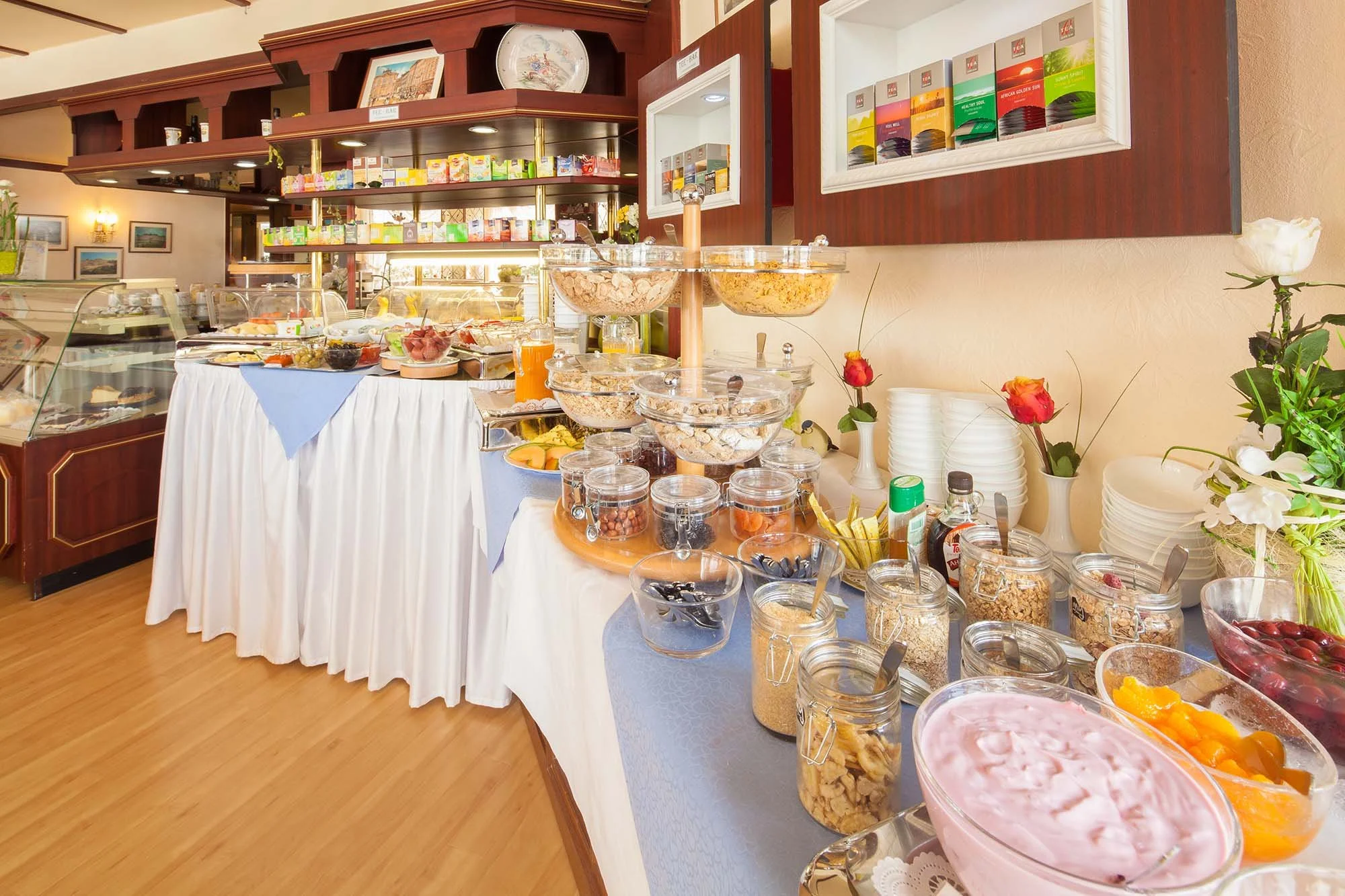 Frühstücksbuffet mit Joghurt, Obst, Müsli und Aufschnitt in einem Café oder Hotel.